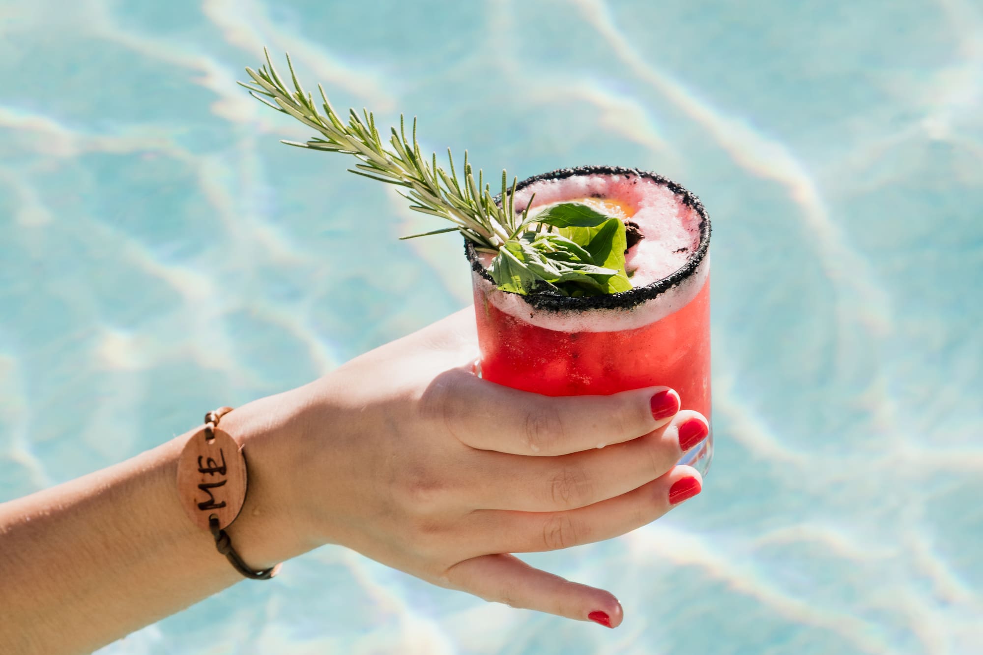 a hand holding a drink in a pool