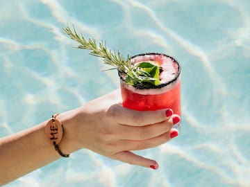 a hand holding a drink in a pool