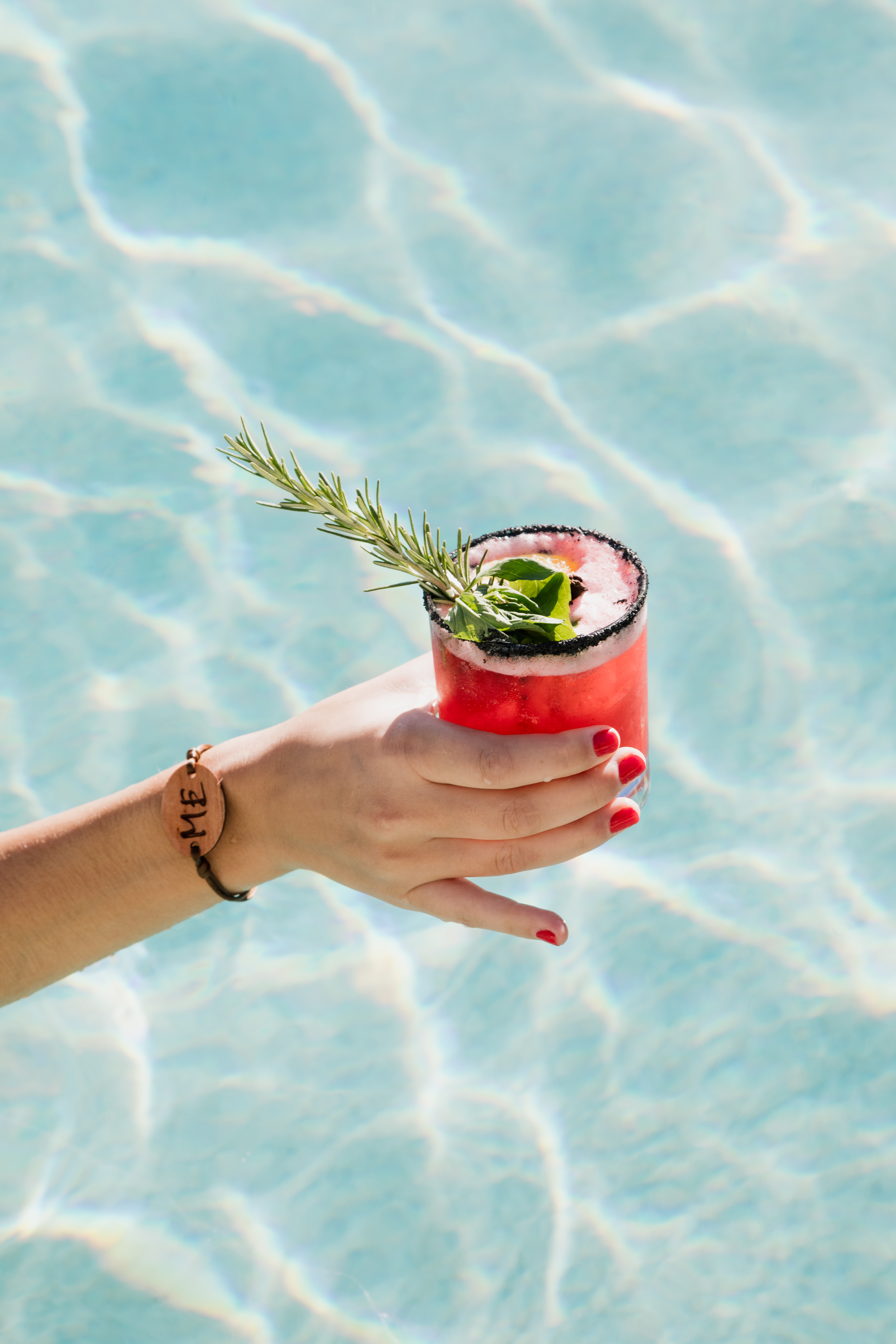 a hand holding a drink in a pool