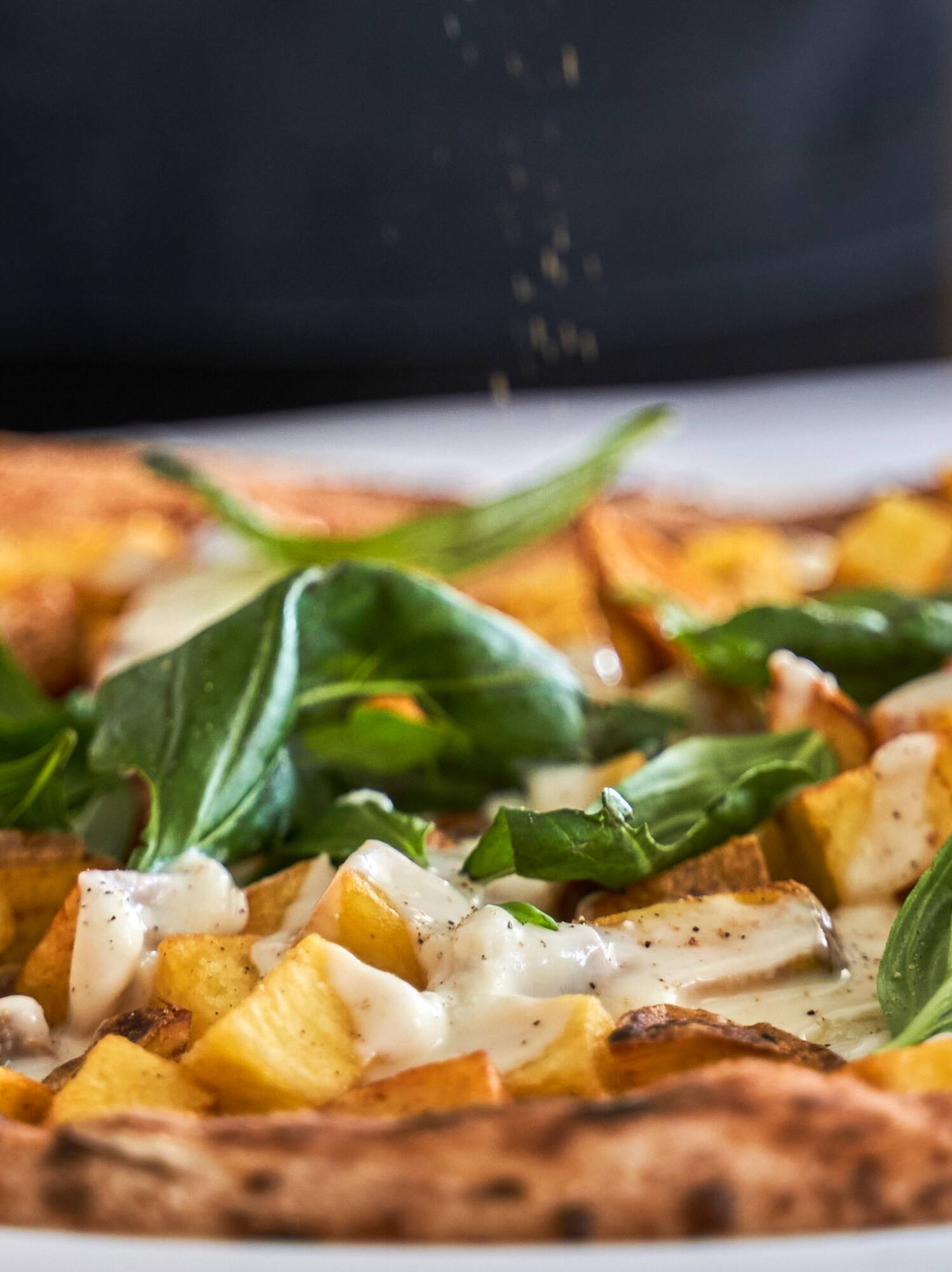 a pizza with potatoes and basil on a plate
