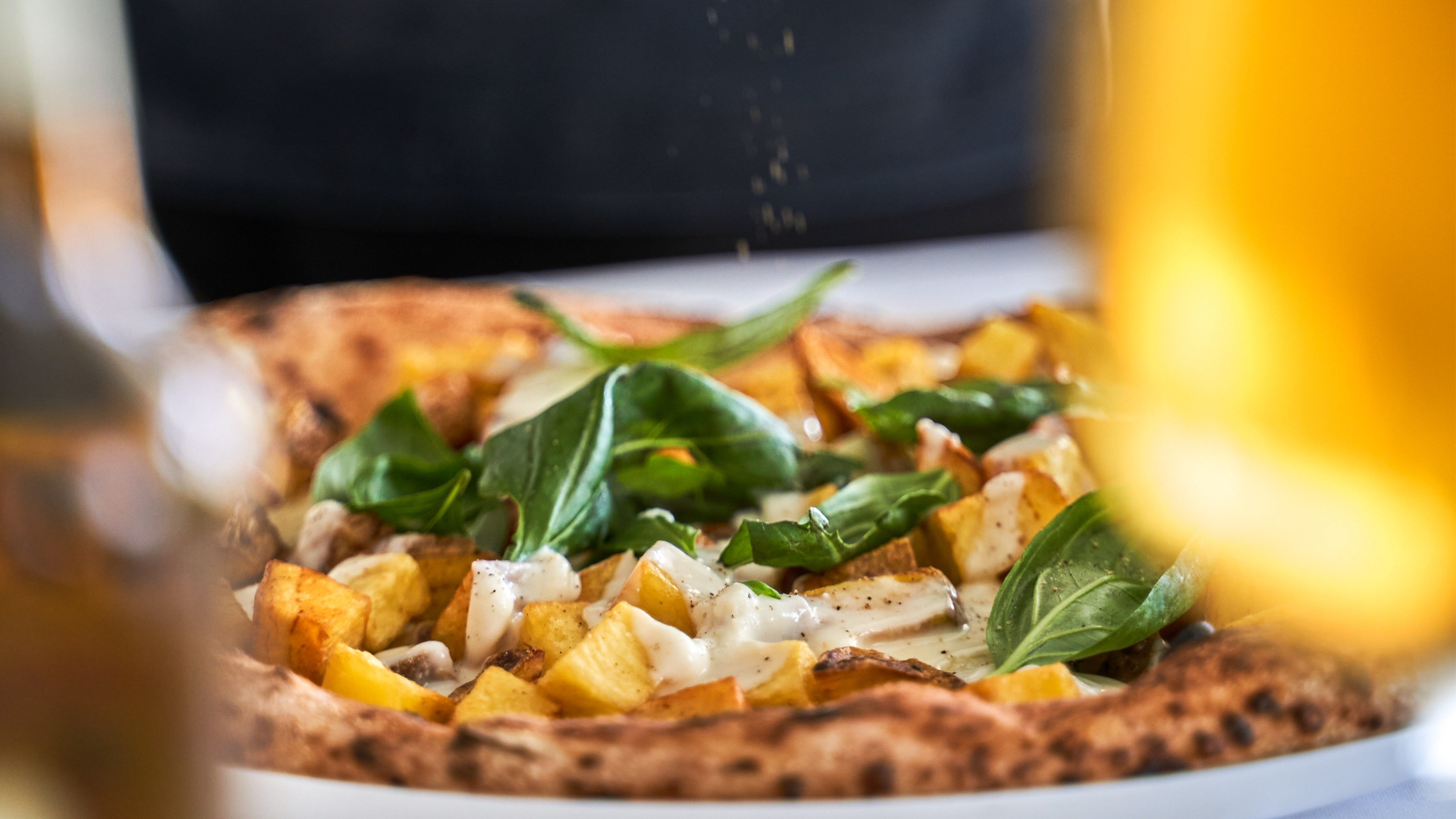 a pizza with potatoes and basil on a plate