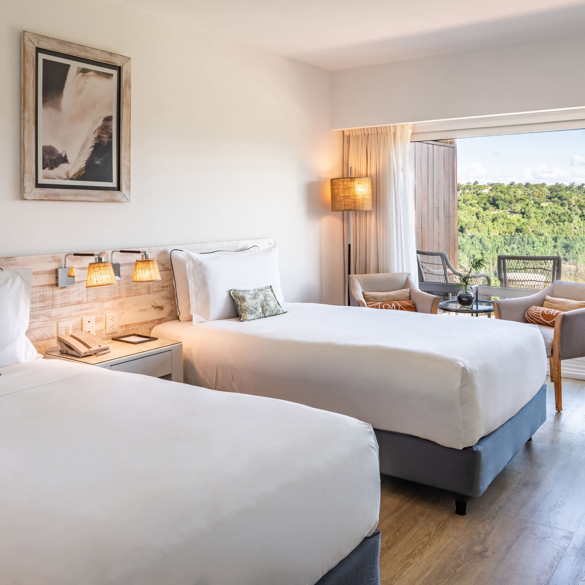 a room with two beds and a table with chairs and a balcony