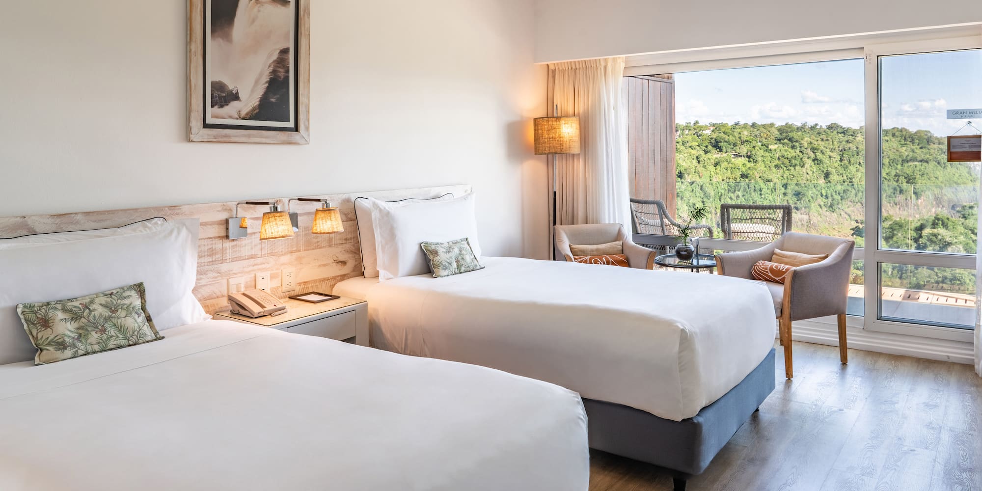 a room with two beds and a table with chairs and a balcony