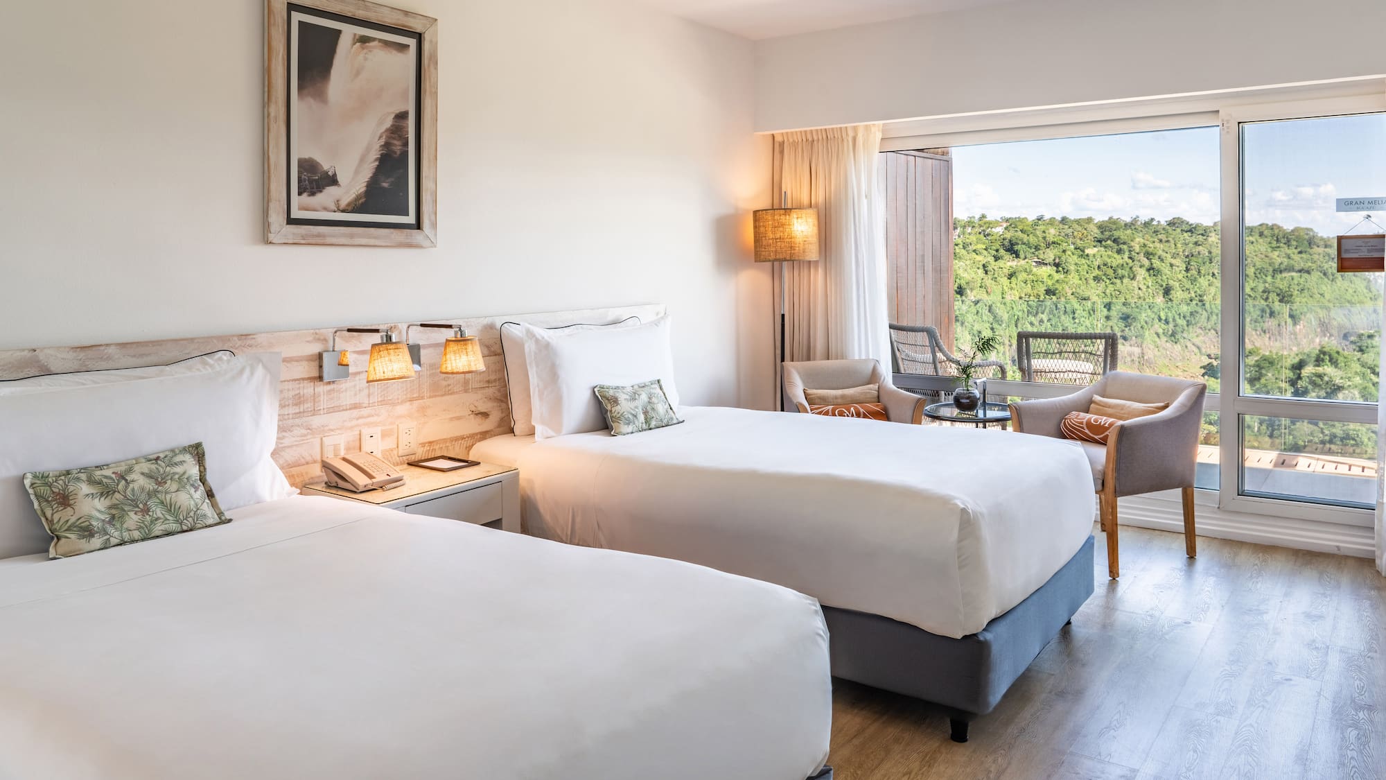 a room with two beds and a table with chairs and a balcony