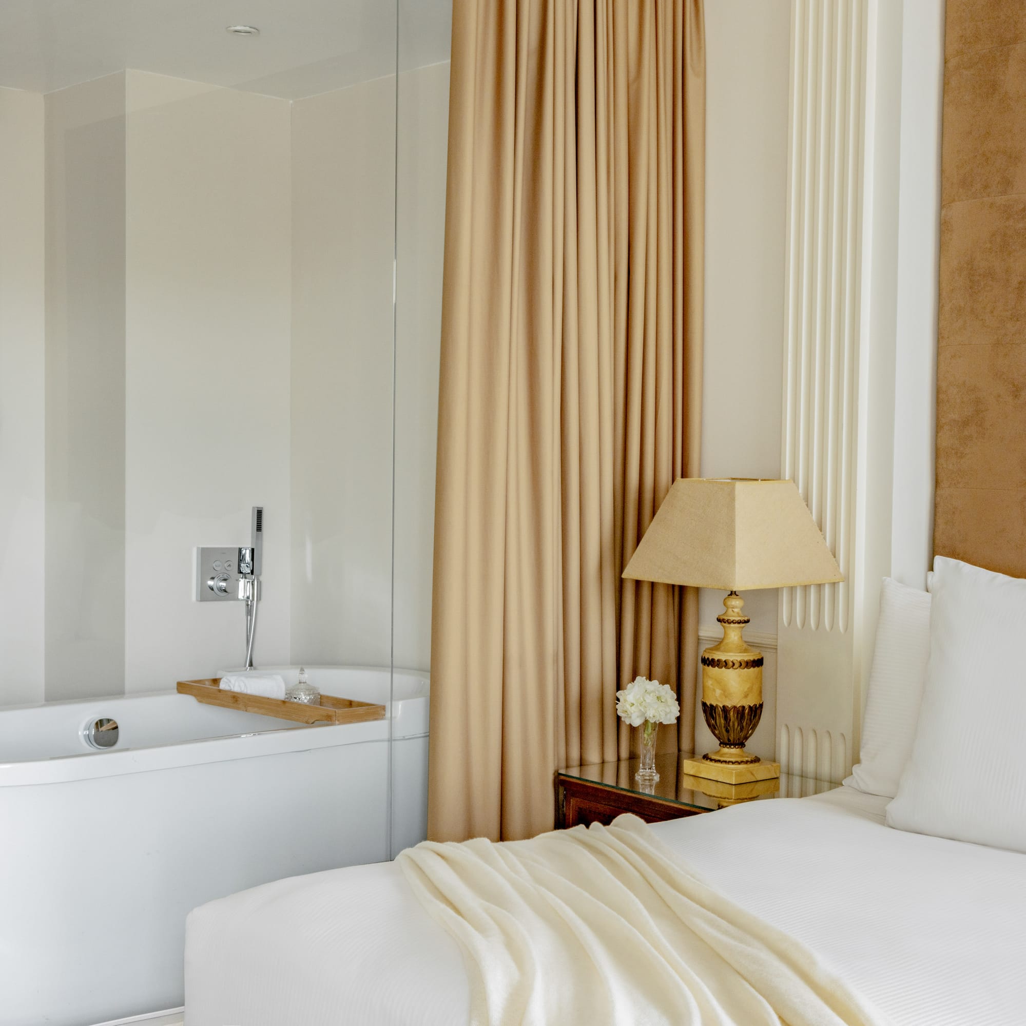 a bed with a lamp next to a bathtub