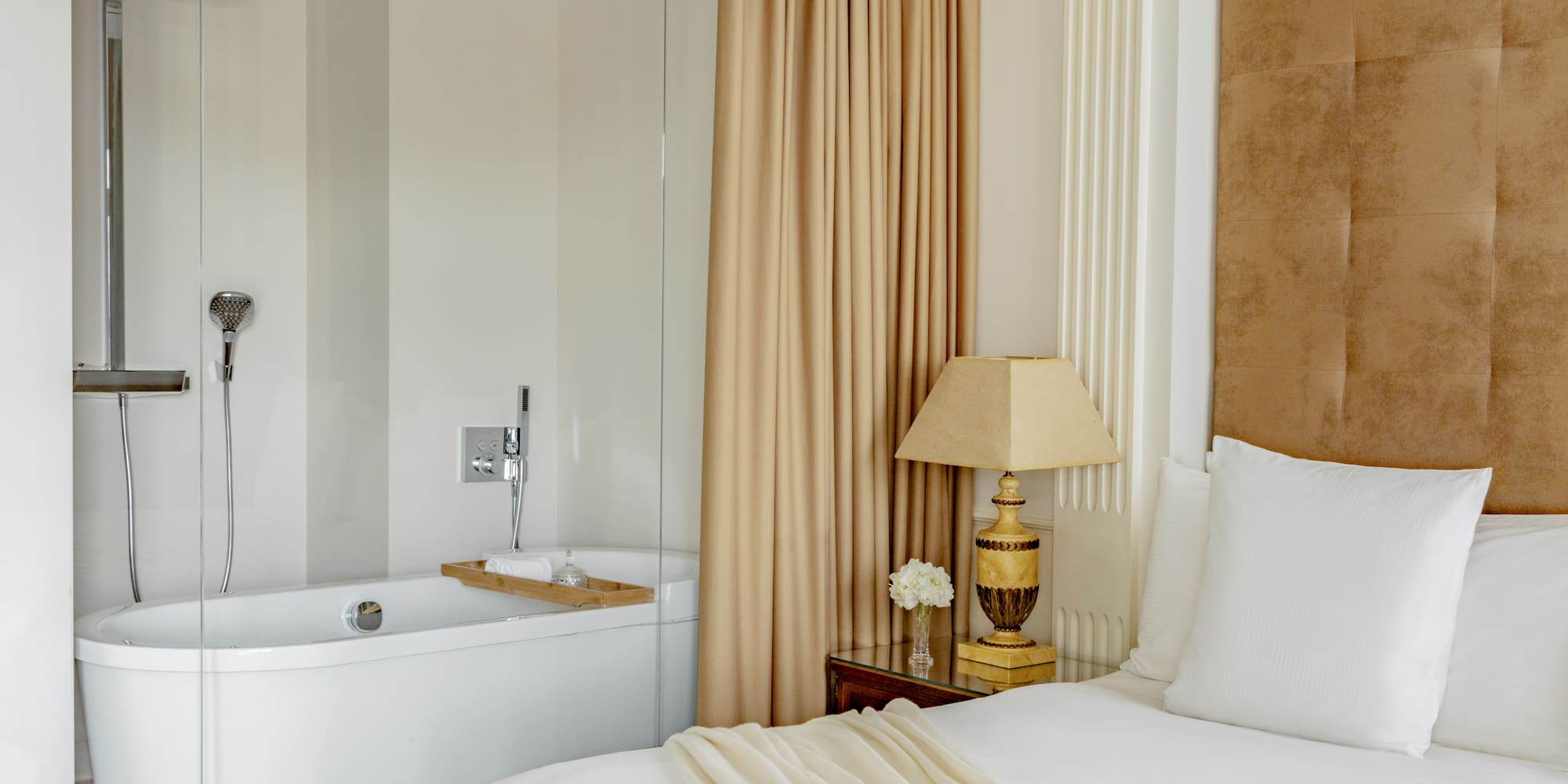 a bed with a lamp next to a bathtub