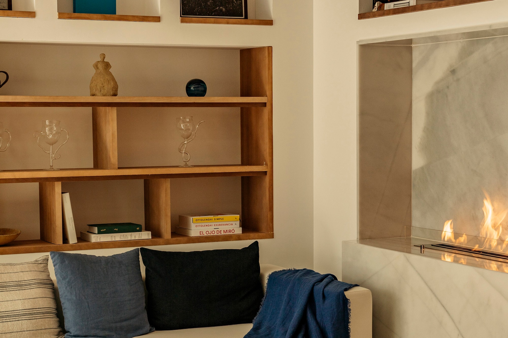 Modern living room: beige sofa, fireplace, wood shelves, exposed beams.