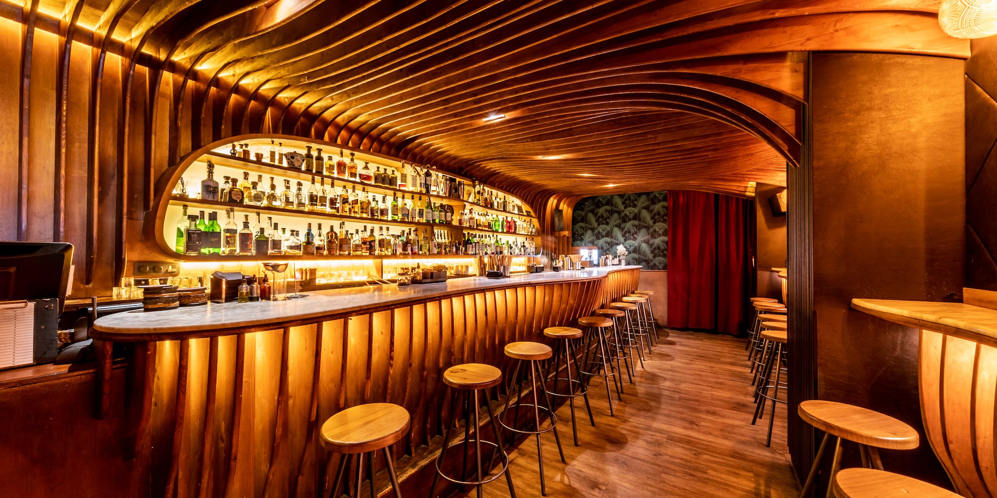 a bar with stools and bottles on the shelves