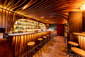 a bar with stools and bottles on the shelves