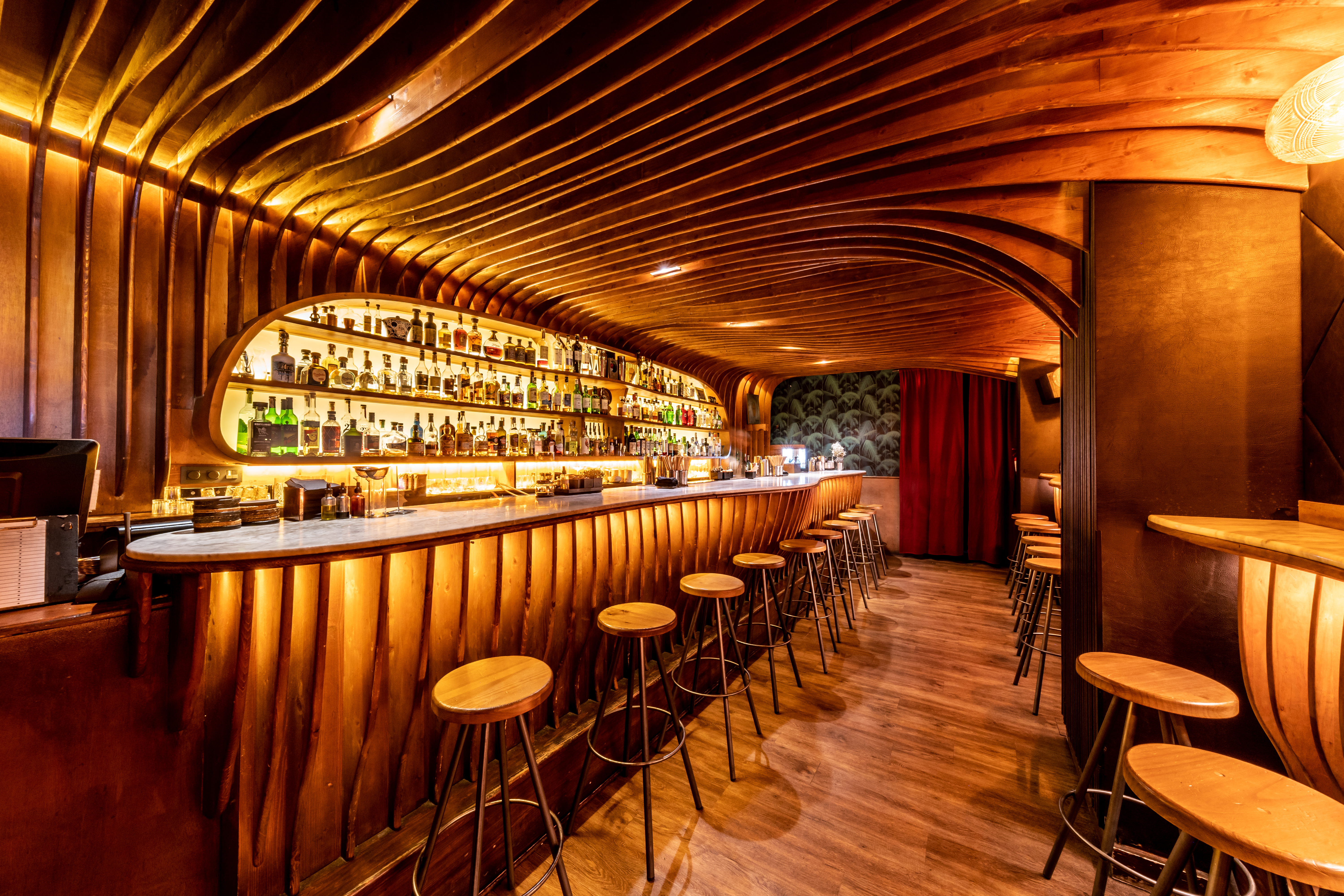 a bar with stools and bottles on the shelves