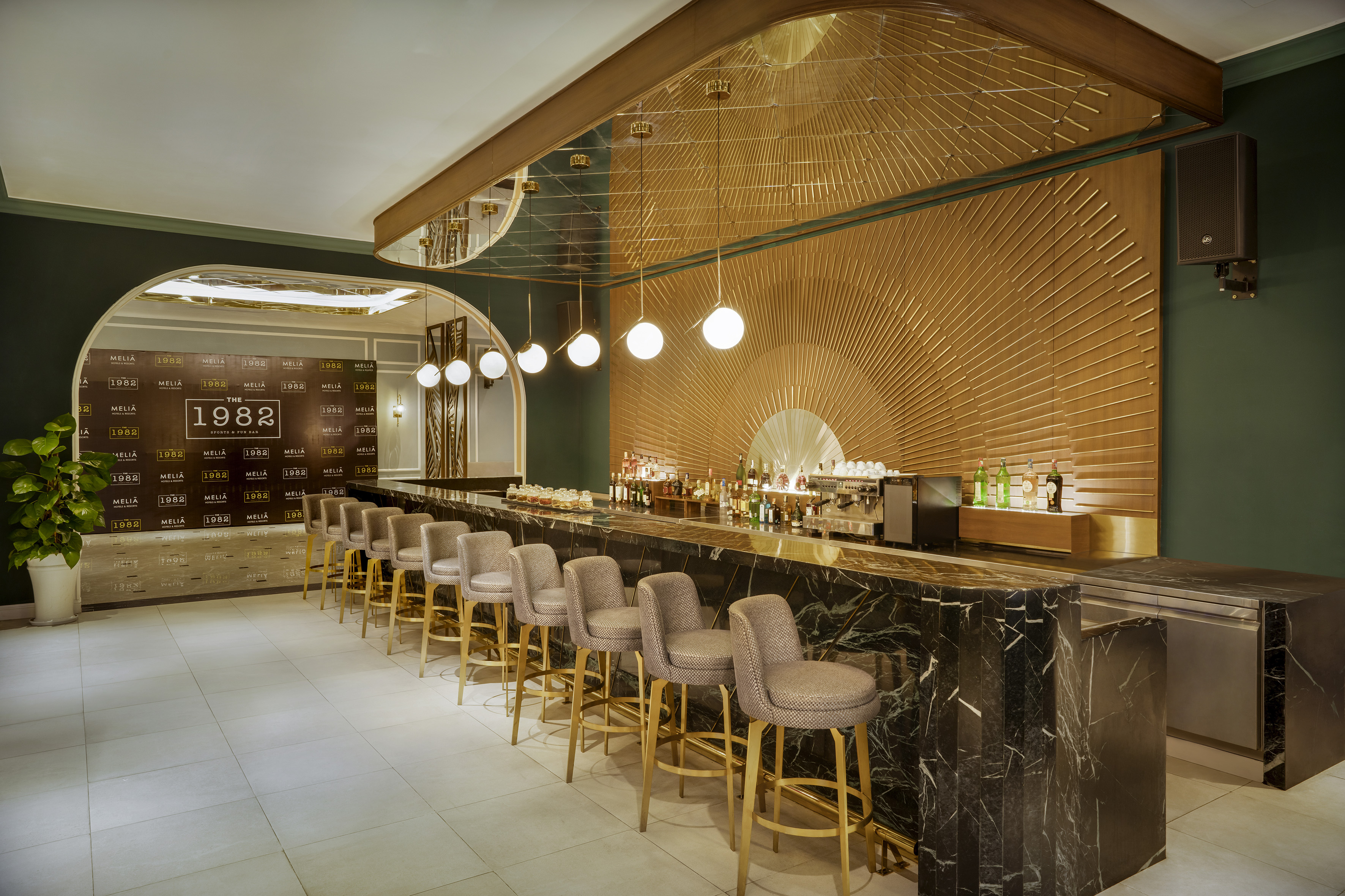 Meliá "The 1982" bar, black marble counter, gold sunburst wall design.