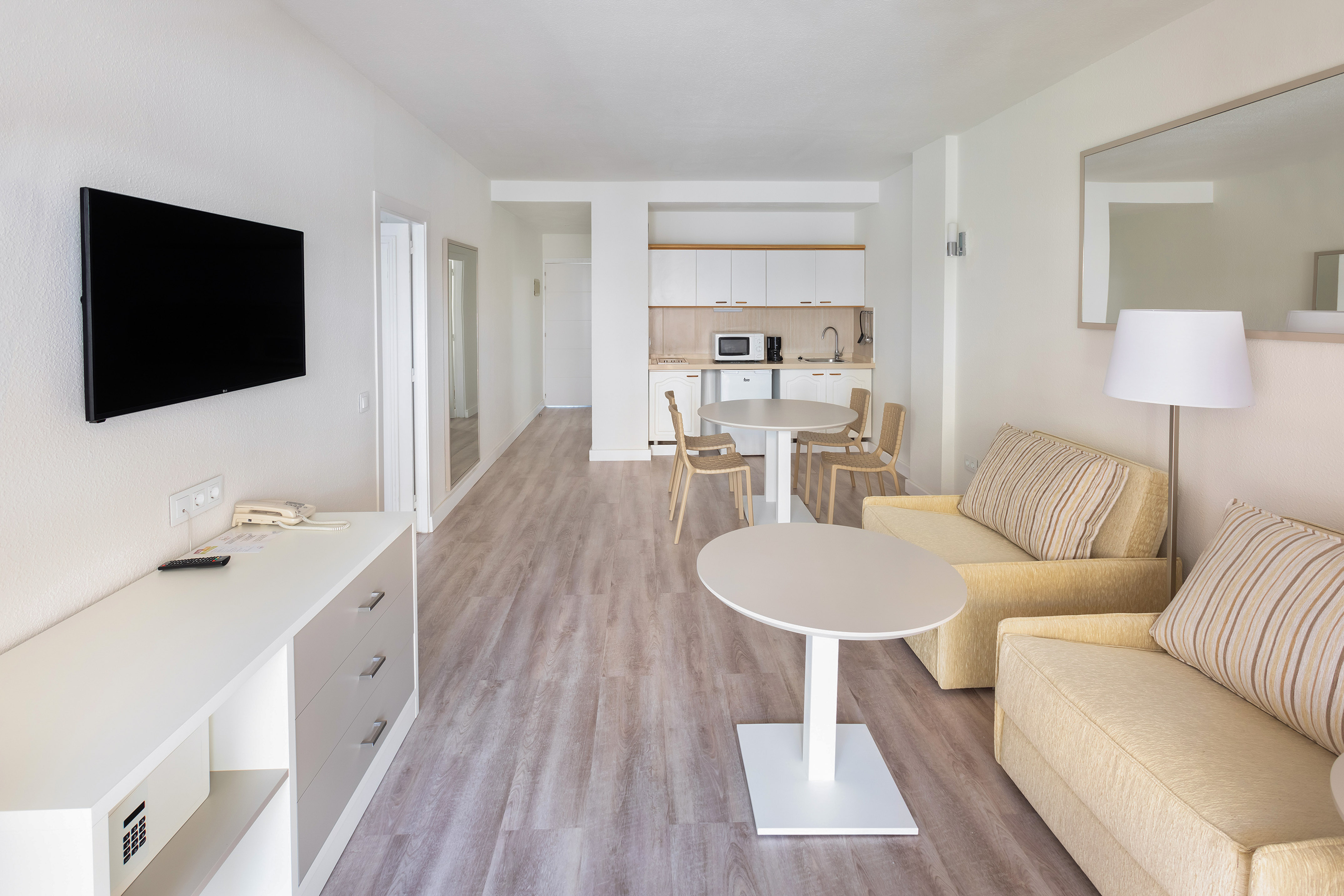 Spacious studio apartment with kitchenette, living room sofas, and dining area.
