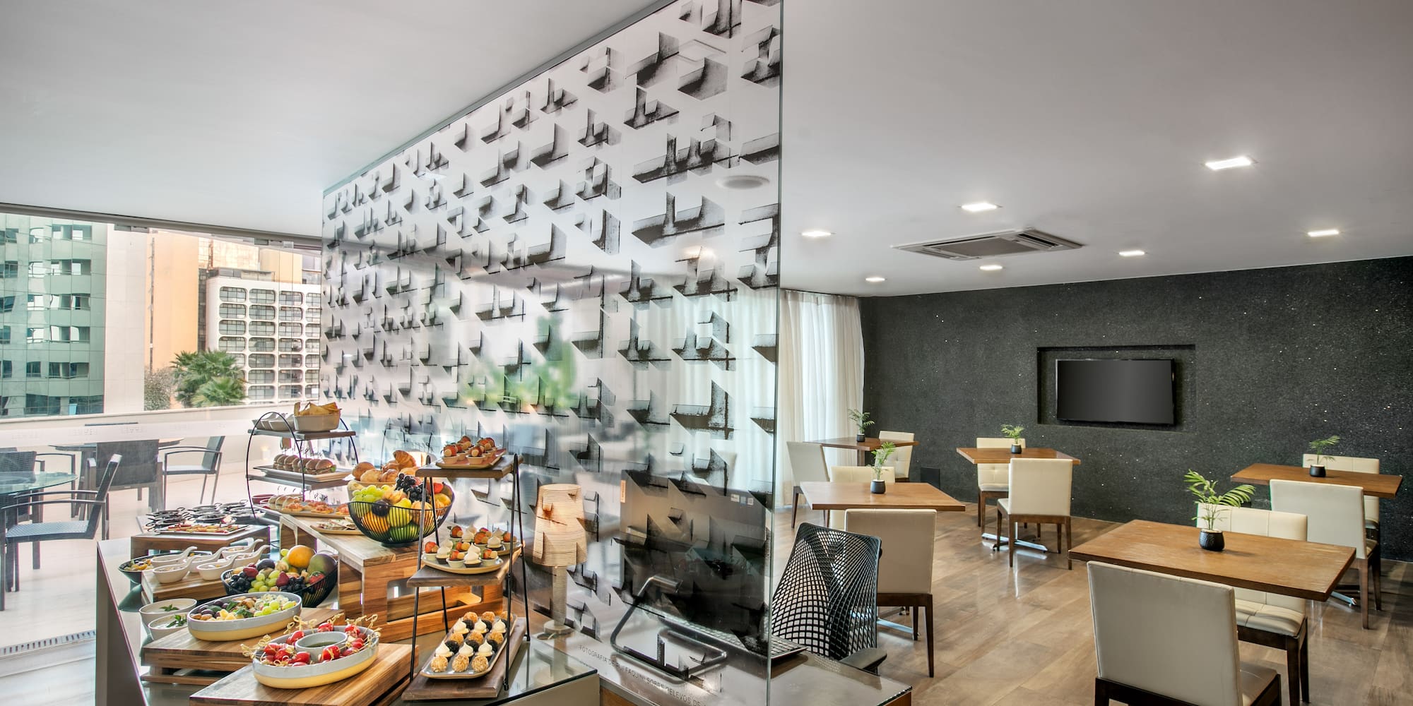 Modern hotel breakfast buffet with fresh food, dining area, and city view.