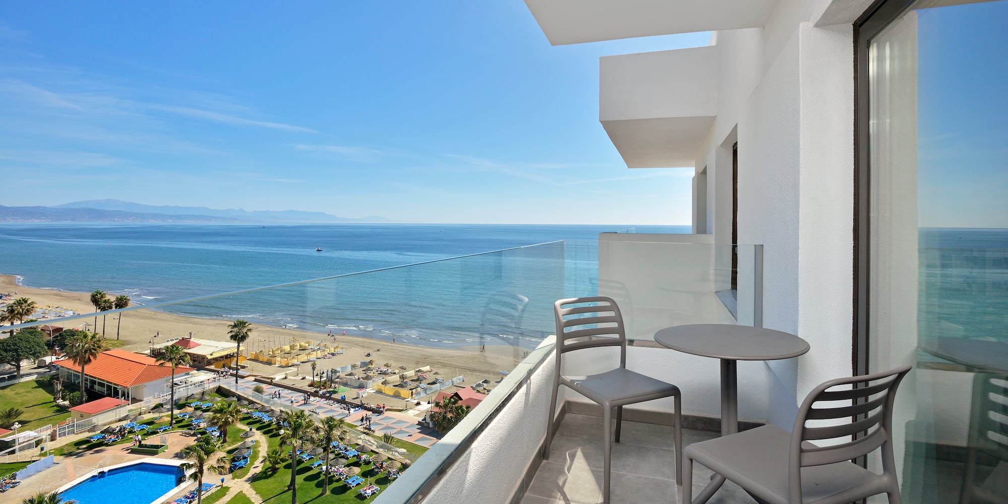 a balcony with chairs and a beach view