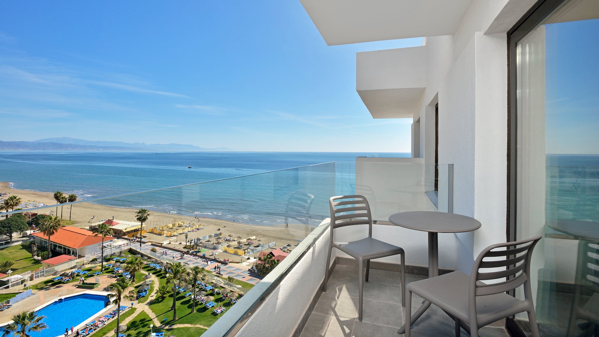 a balcony with chairs and a beach view