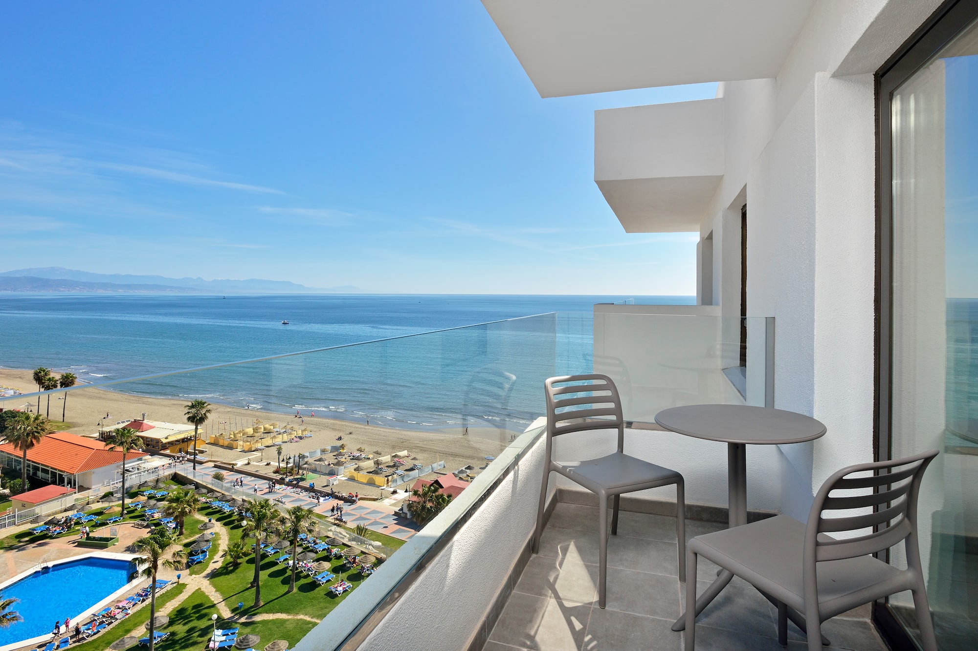 a balcony with chairs and a beach view