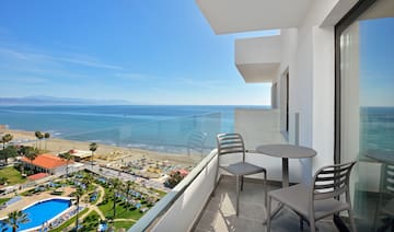 a balcony with chairs and a beach view