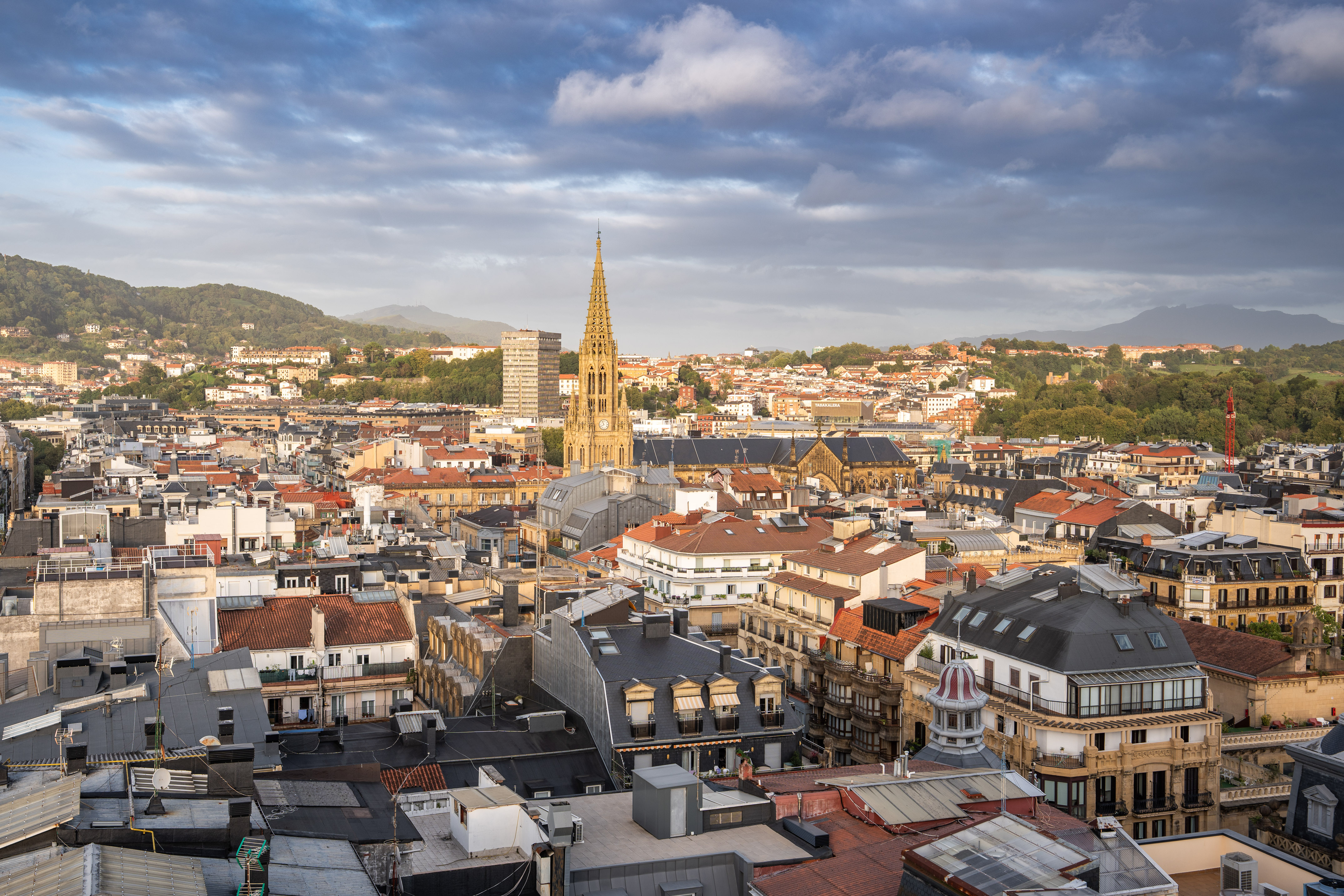 San Sebastián cityscape with prominent cathedral spire and cloudy sky.