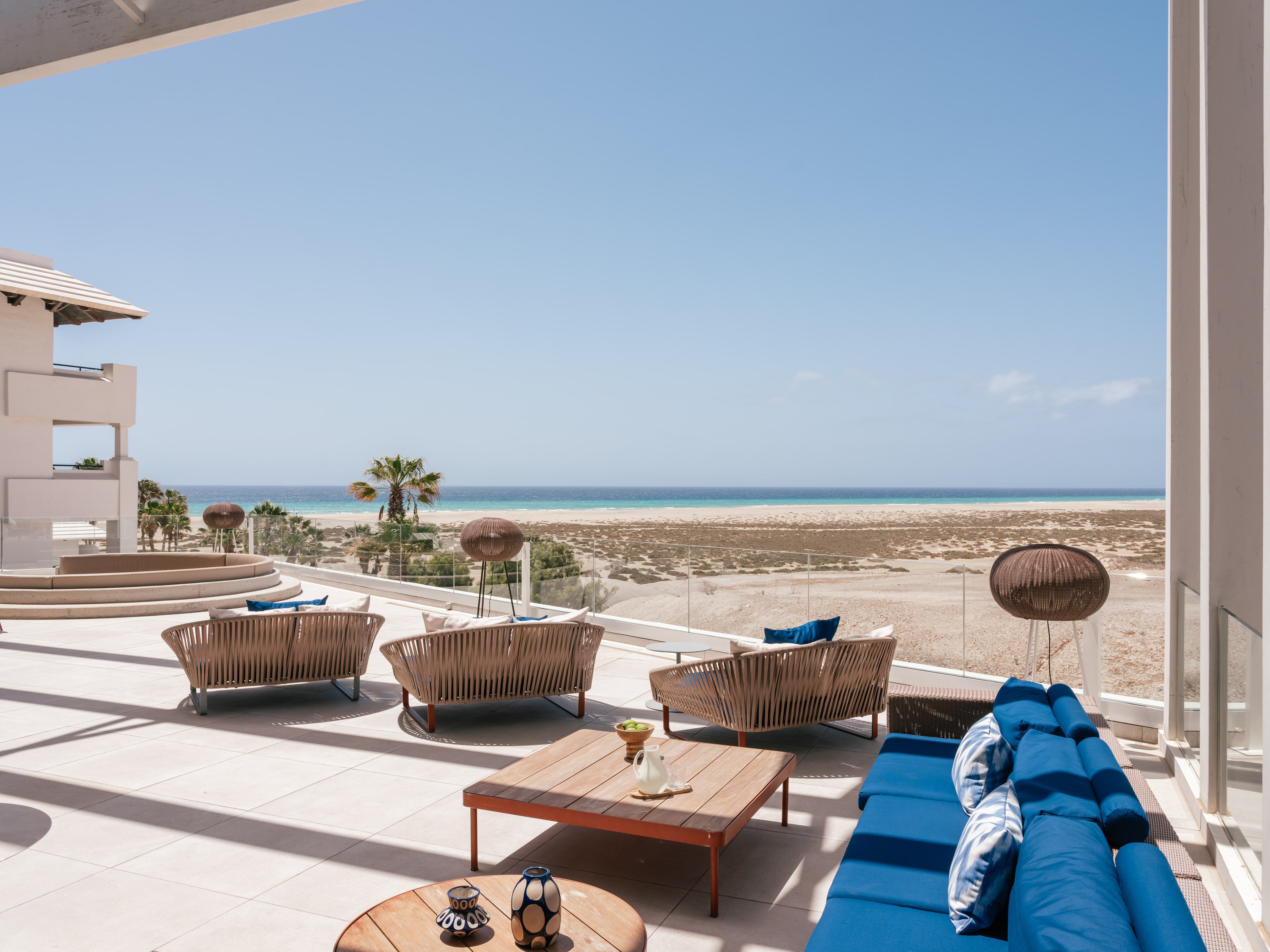 Beachfront resort patio with modern lounge furniture and ocean view.