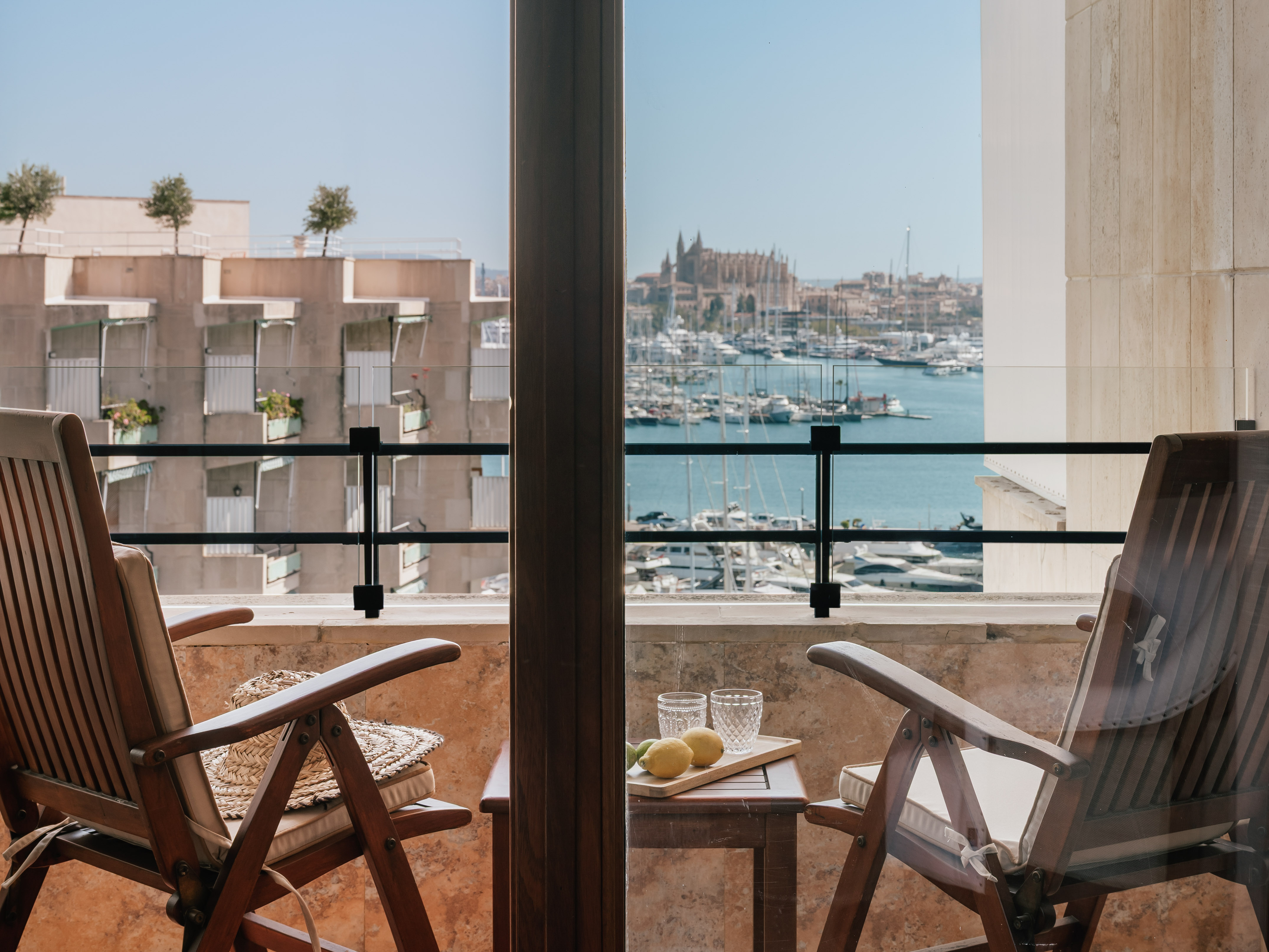 Balcony with chairs, harbor view of Palma Cathedral and yachts.