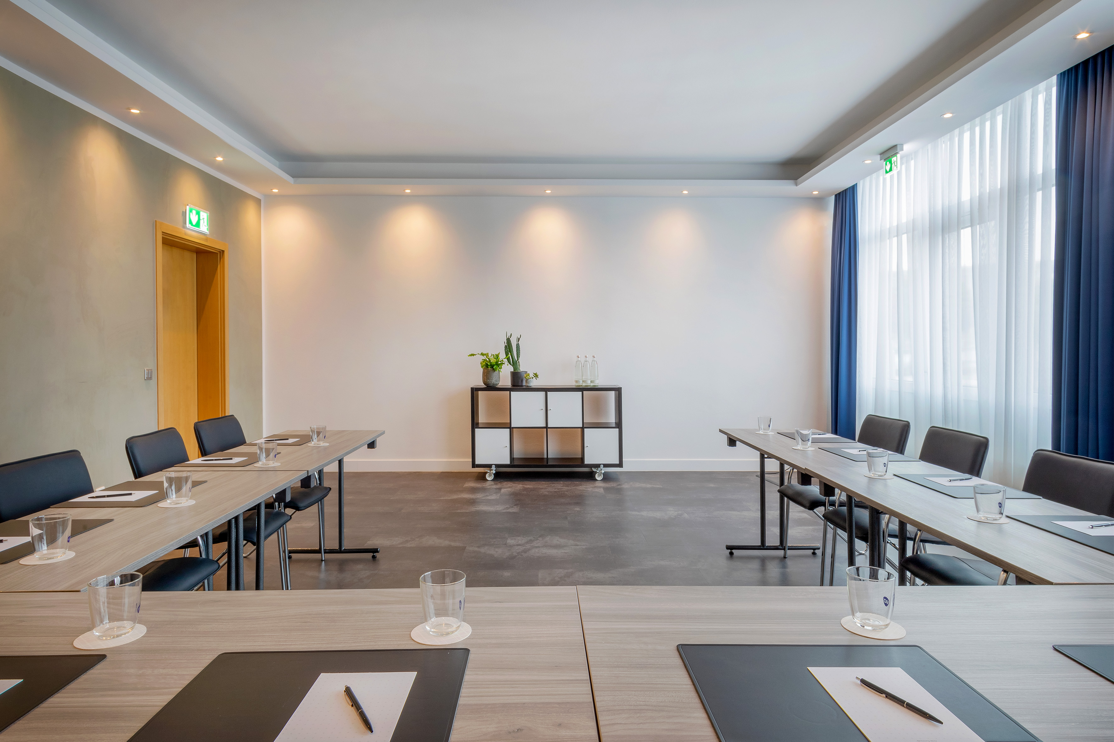 Modern conference room with arranged tables, chairs, and bright window.