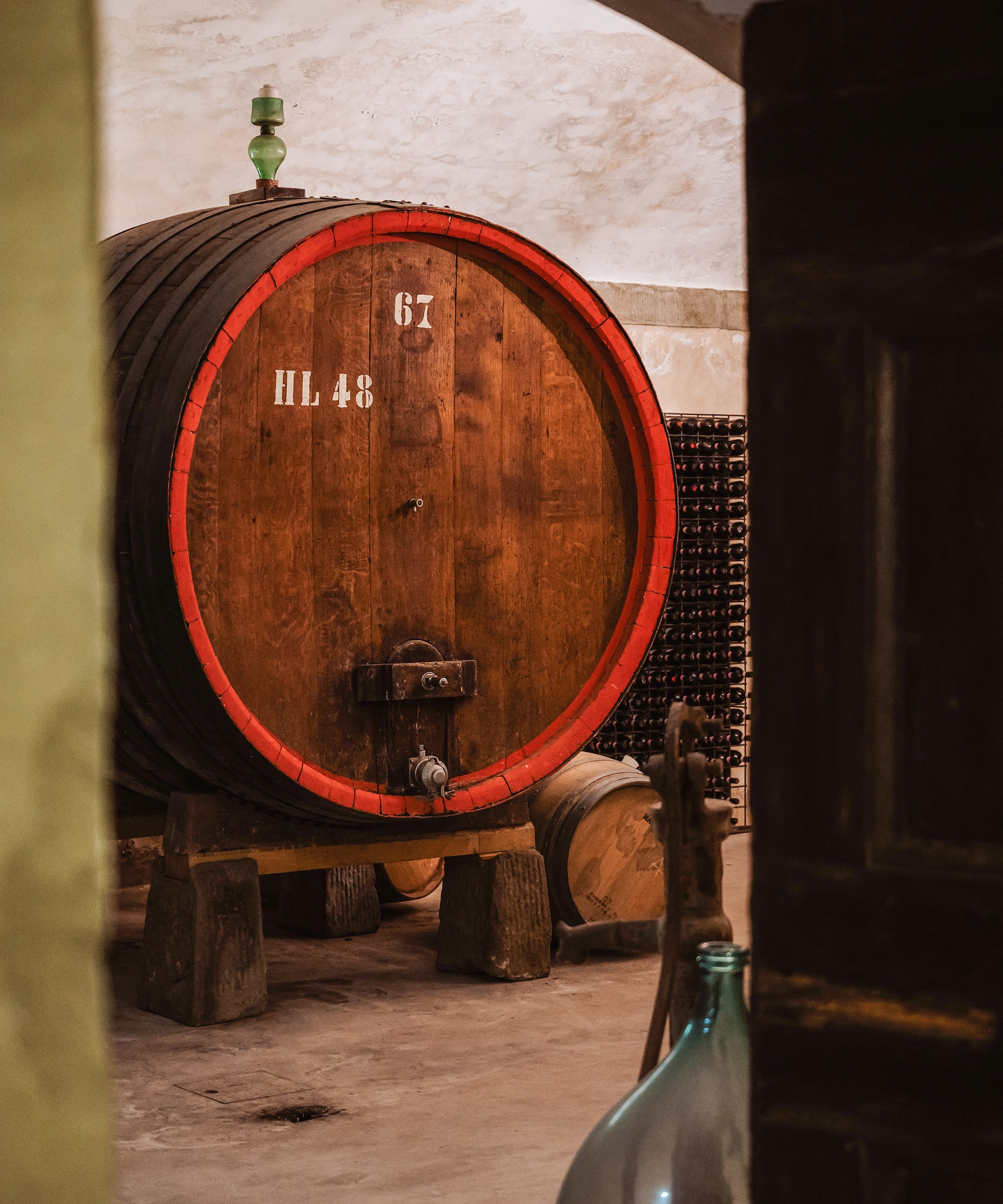 Numbered oak wine barrel HL 48 with red band in a rustic wine cellar.