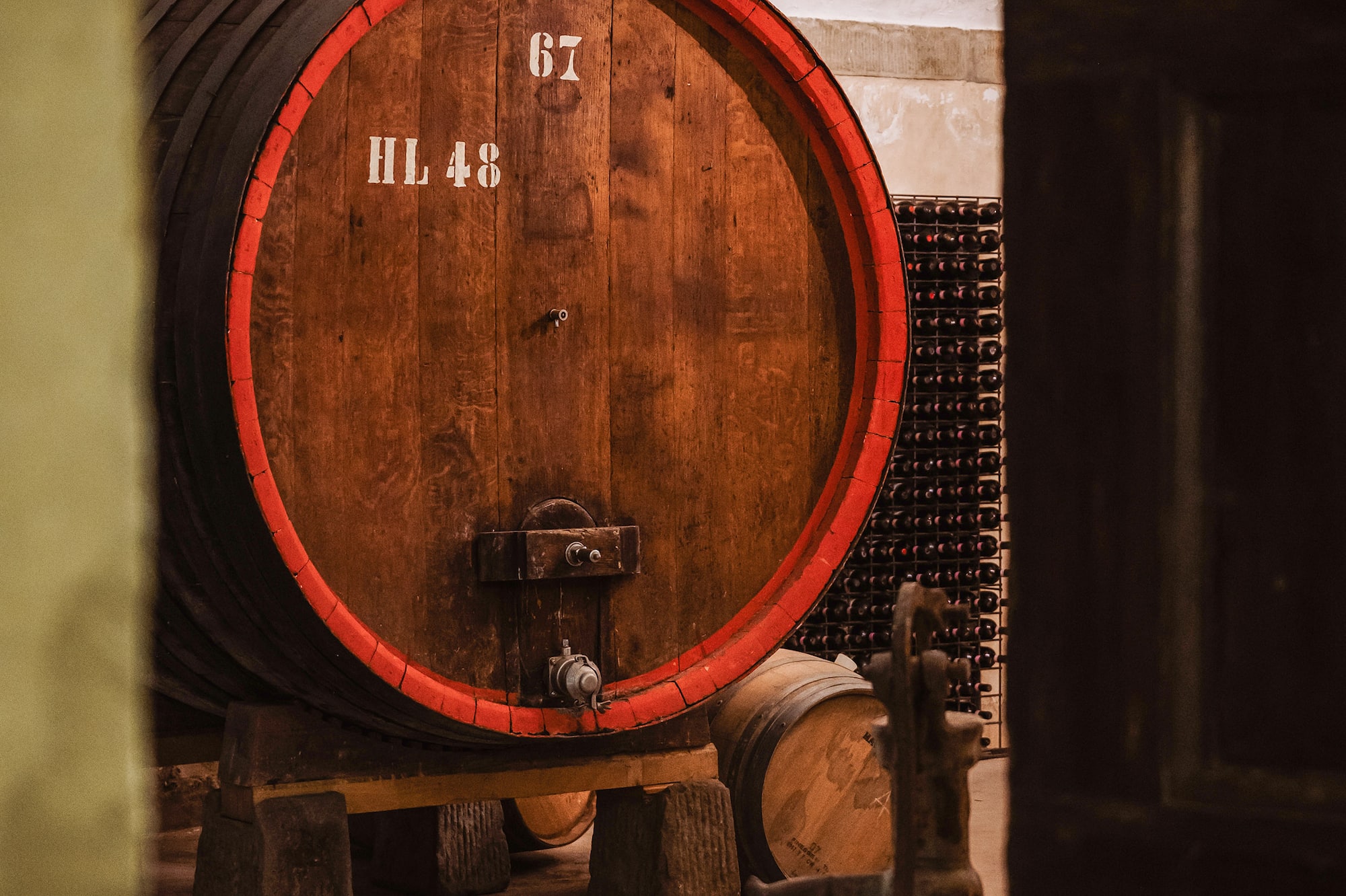 Numbered oak wine barrel HL 48 with red band in a rustic wine cellar.