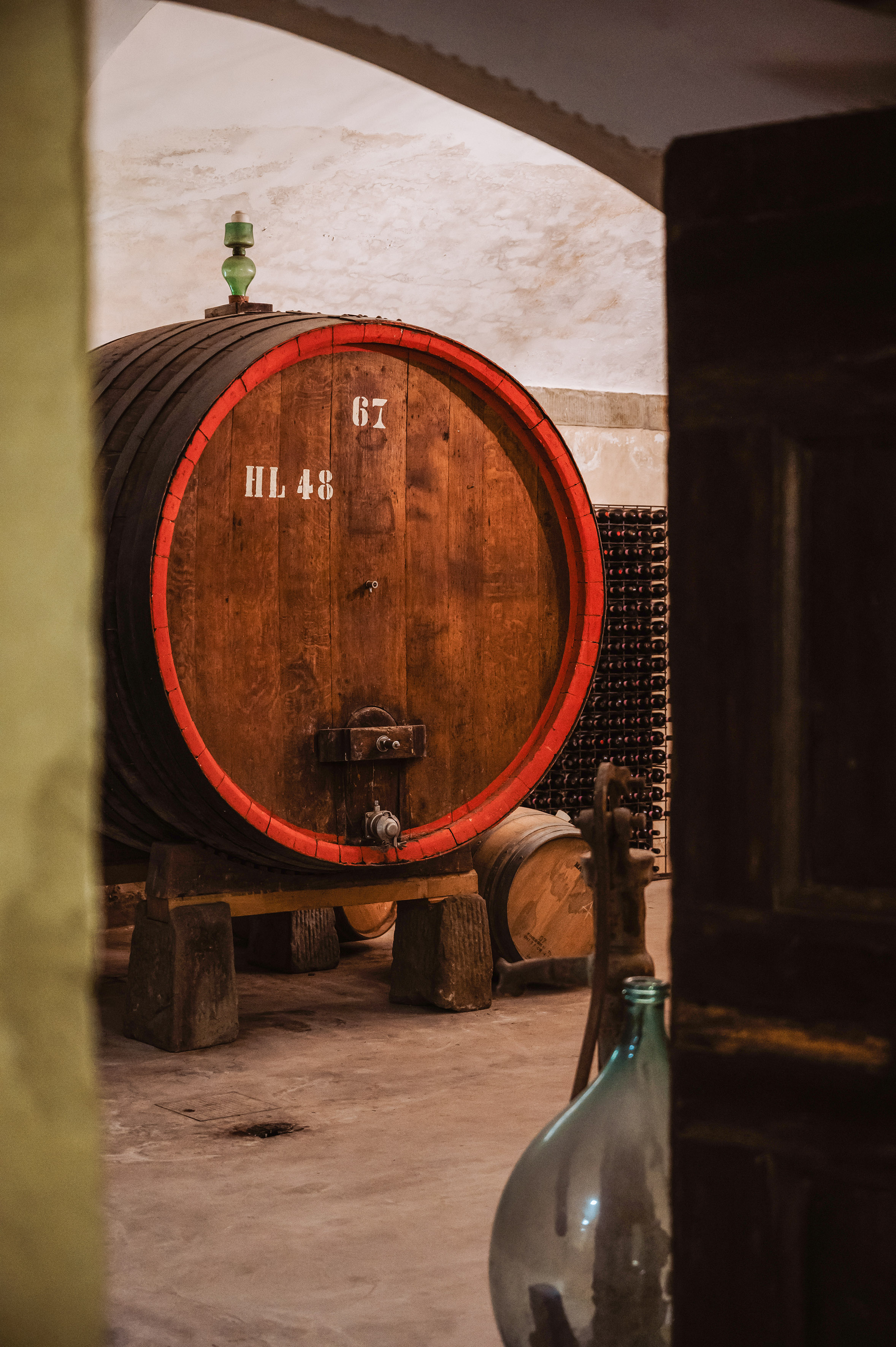 Numbered oak wine barrel HL 48 with red band in a rustic wine cellar.