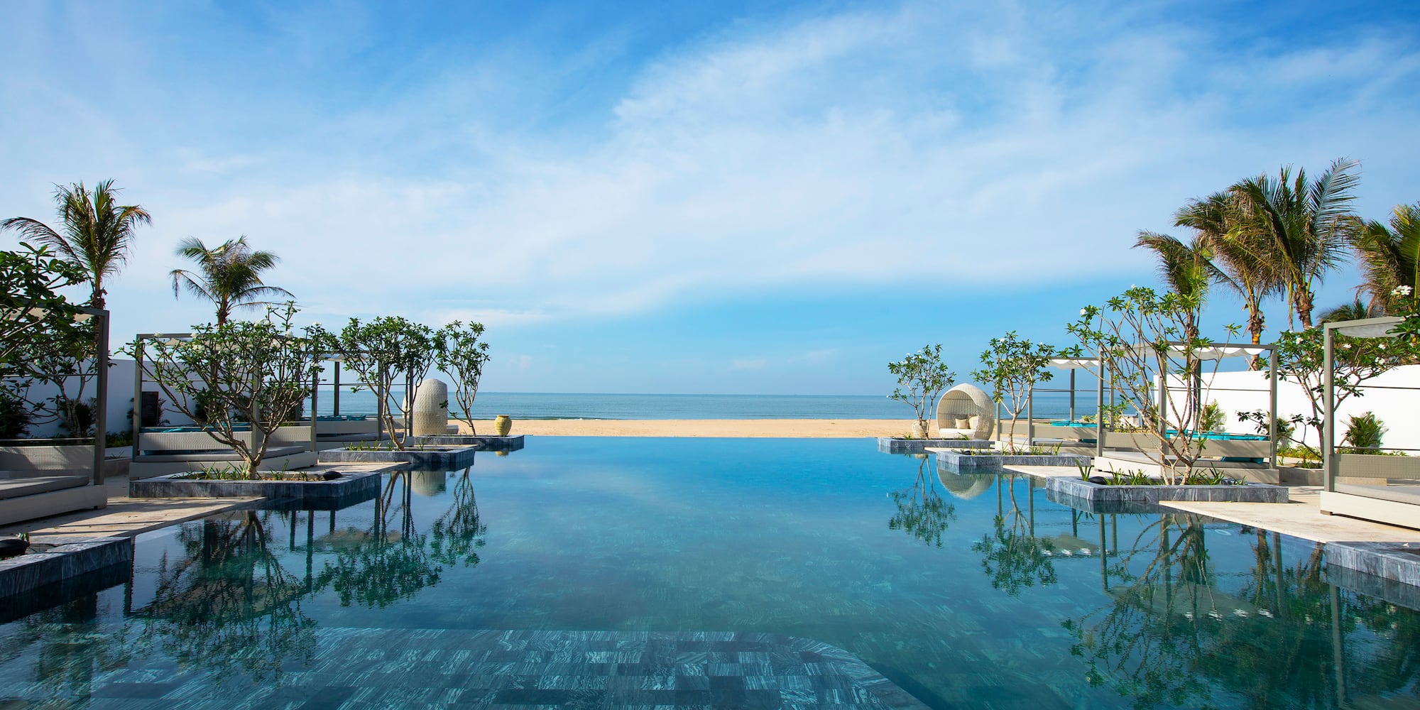 a pool with trees and a beach in the background