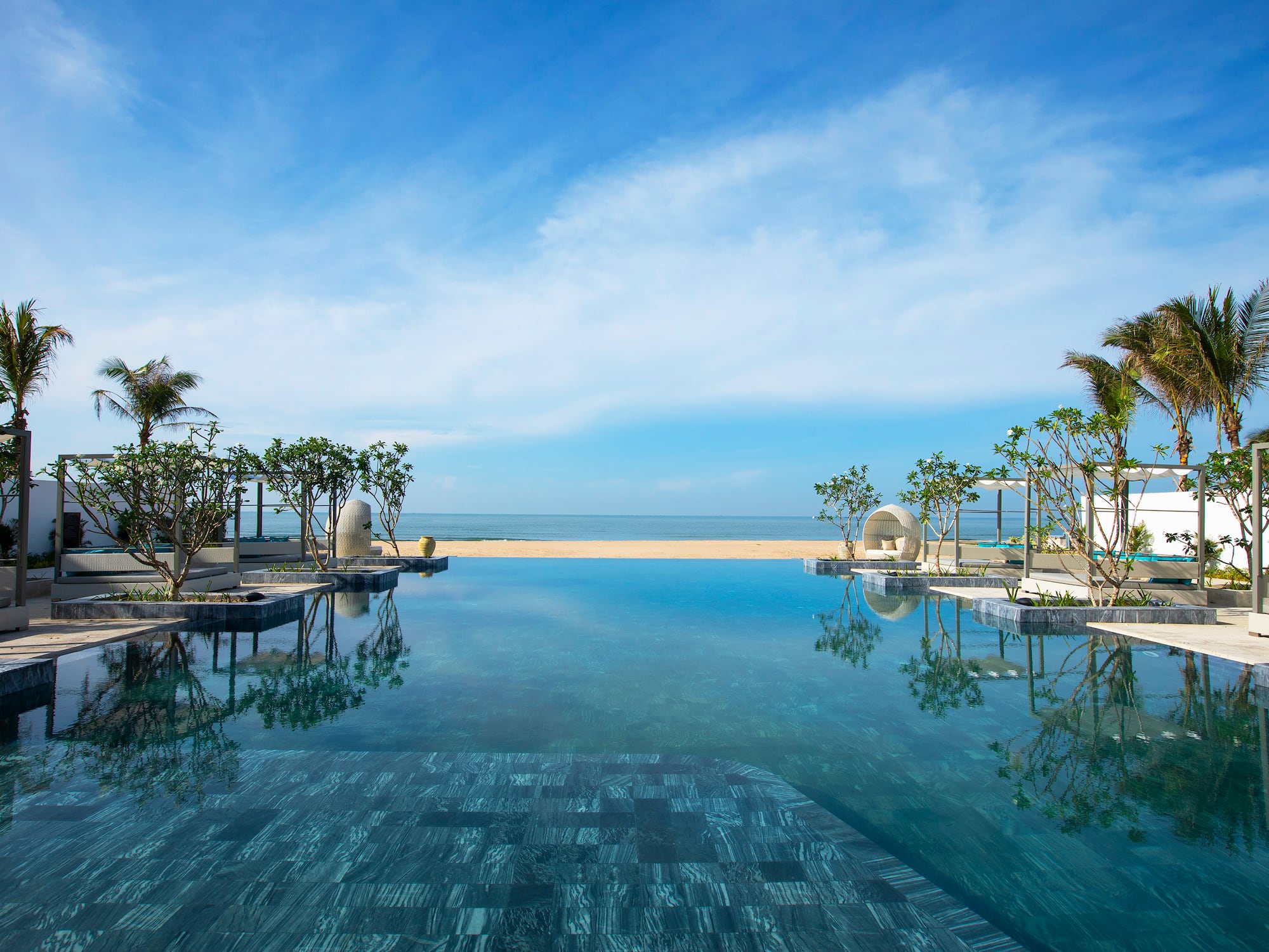 a pool with trees and a beach in the background