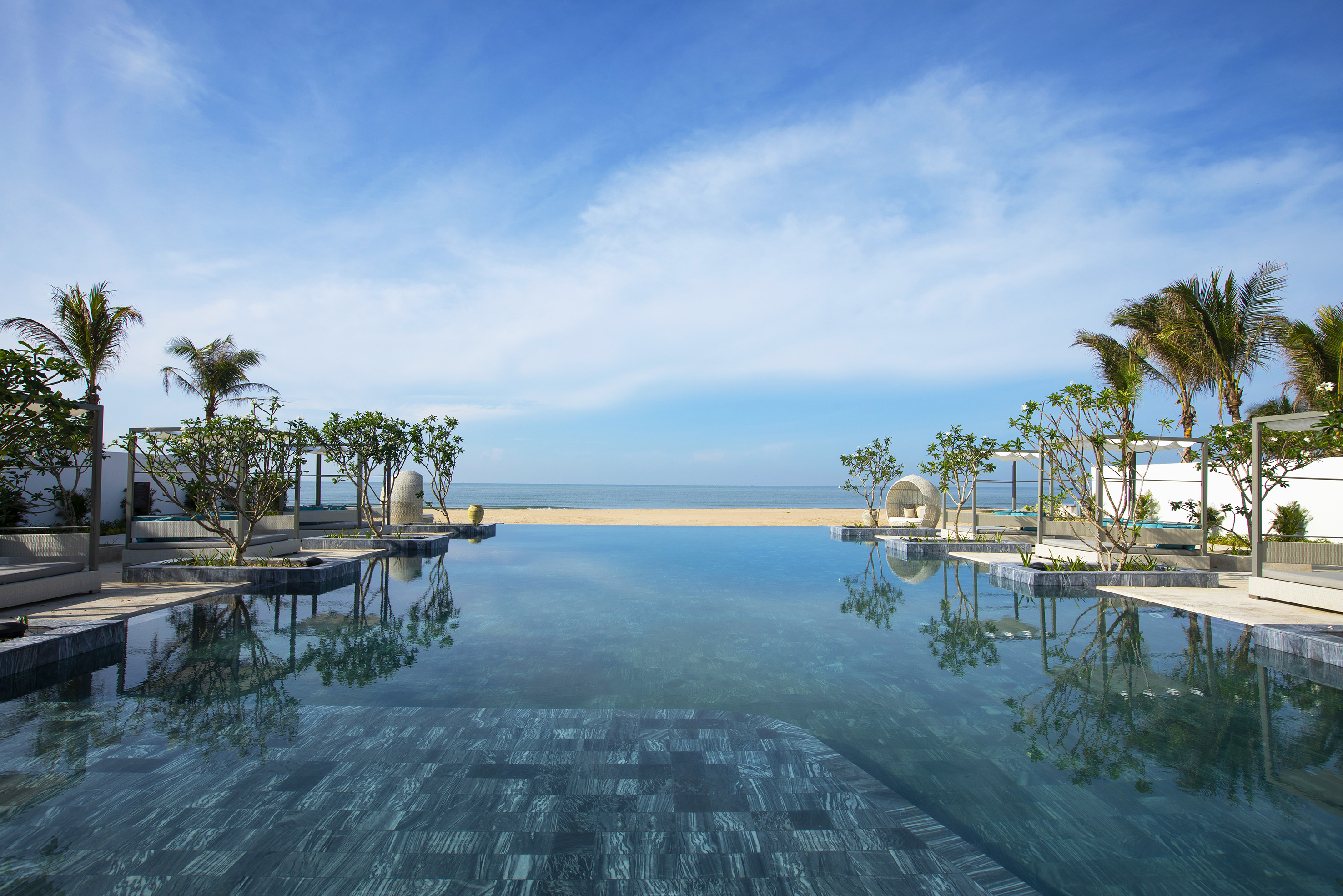 a pool with trees and a beach in the background