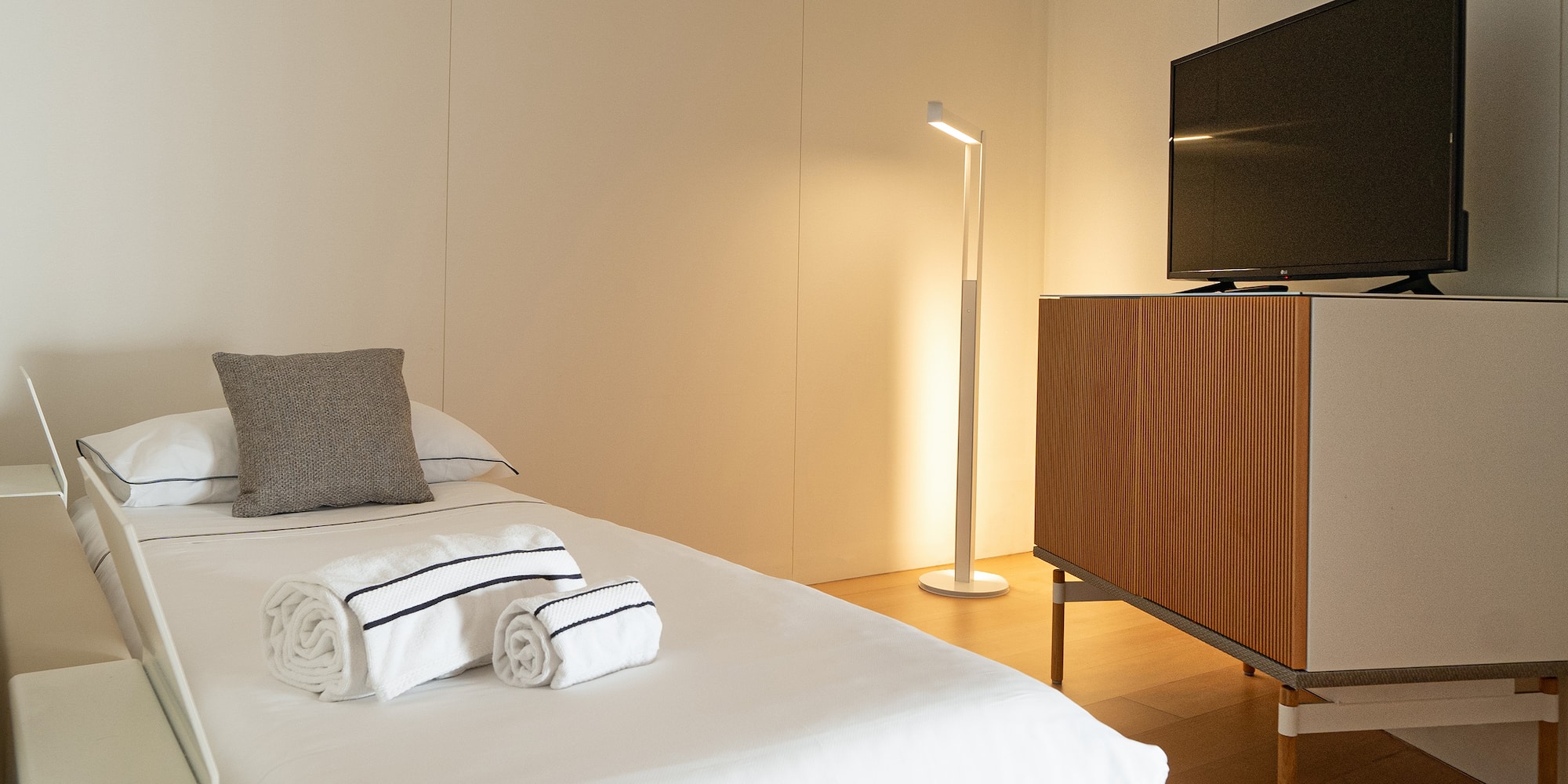 a bed with white sheets and towels on it next to a tv