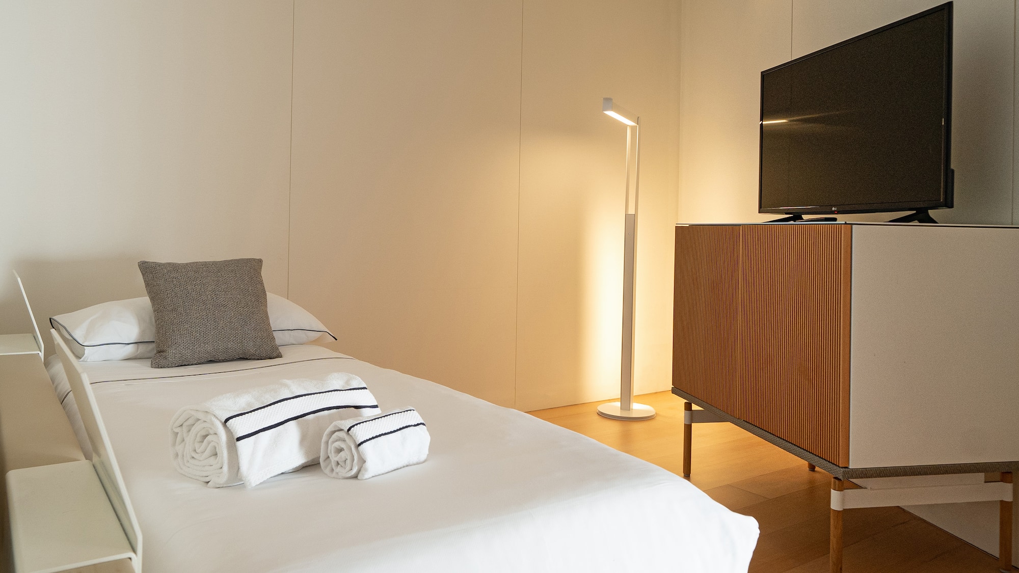 a bed with white sheets and towels on it next to a tv