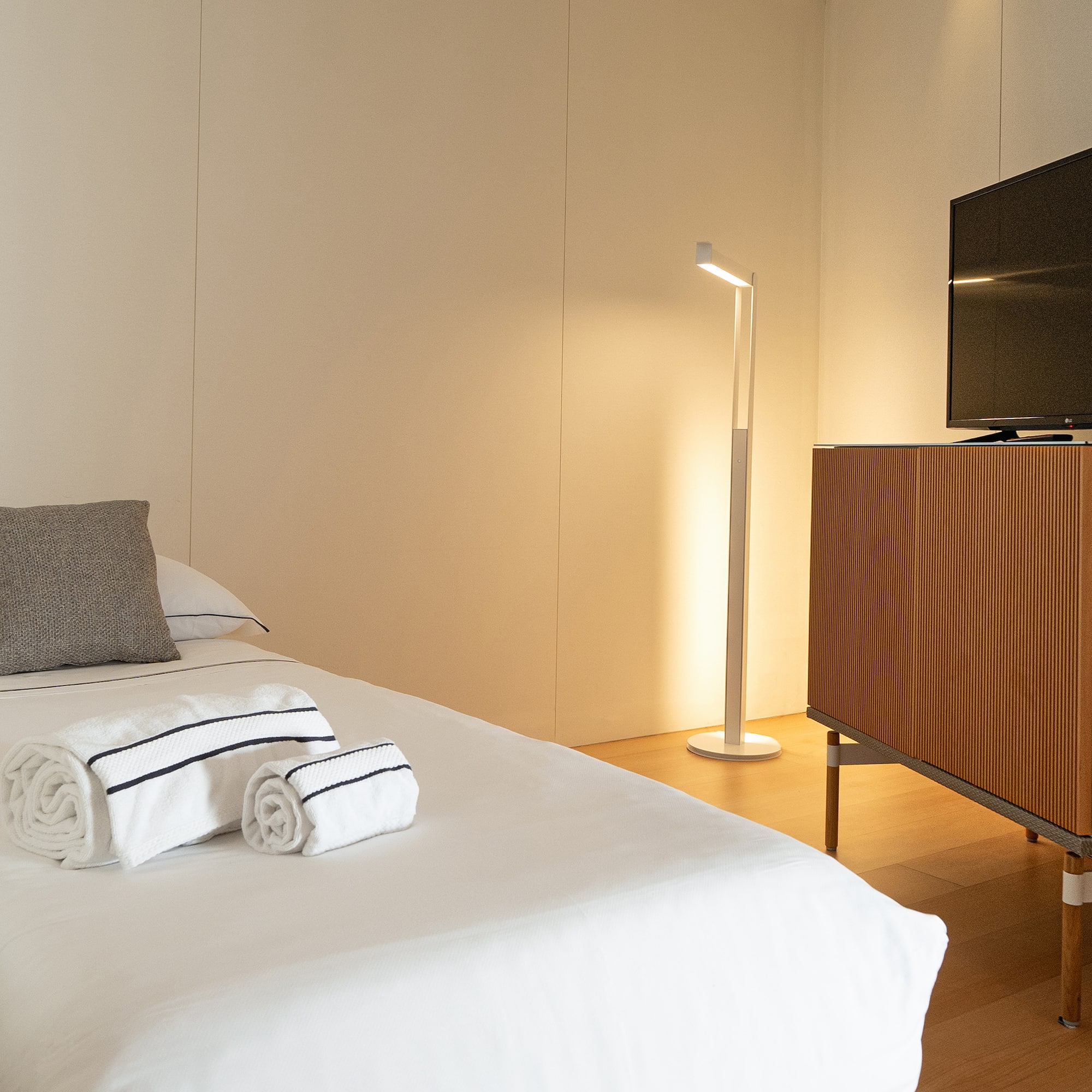 a bed with white sheets and towels on it next to a tv