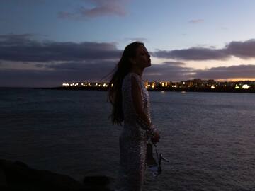 a woman standing on a rock by water with a city in the background