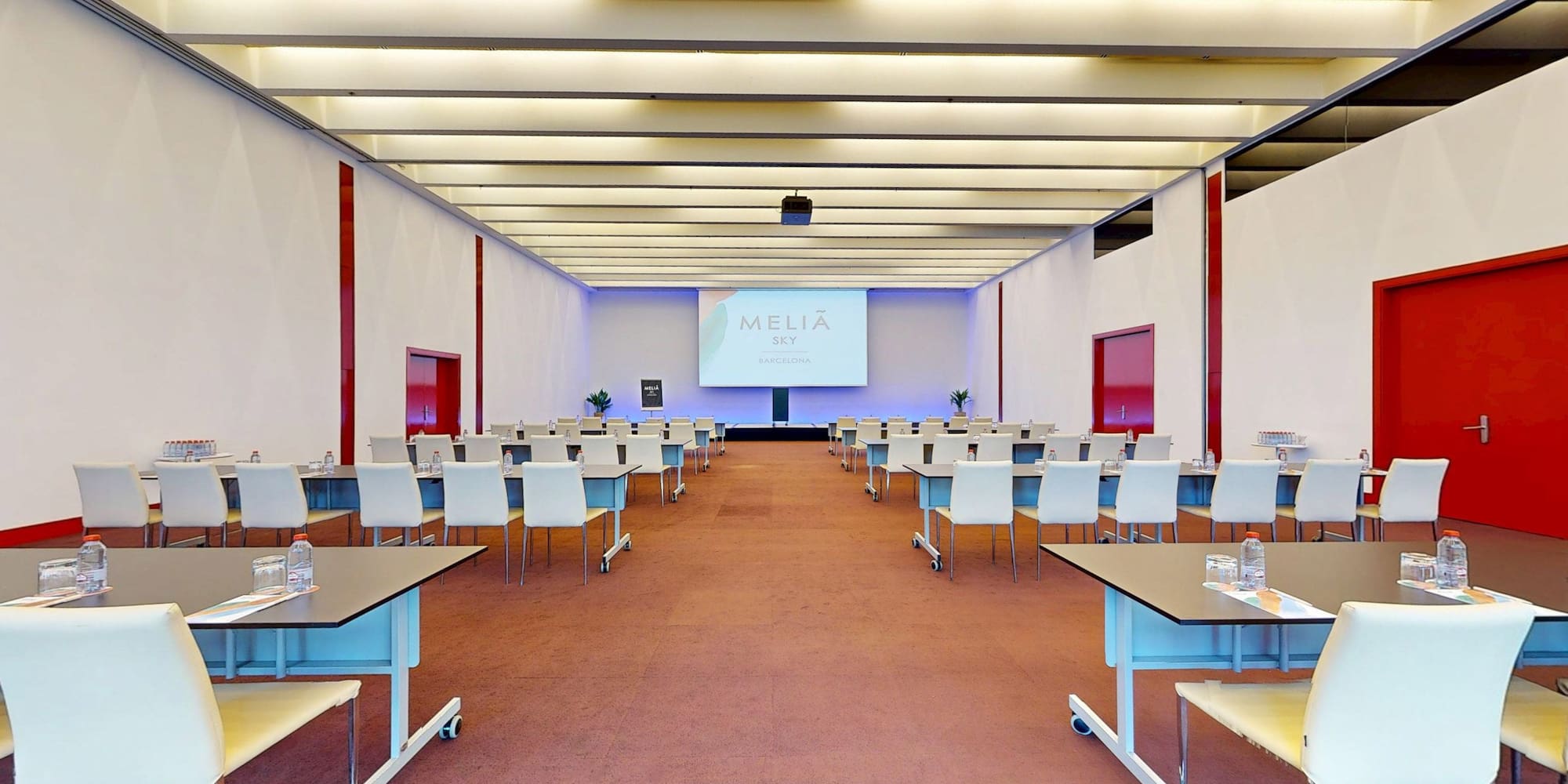 Meliá Sky Barcelona conference room with tables, chairs, and screen display.