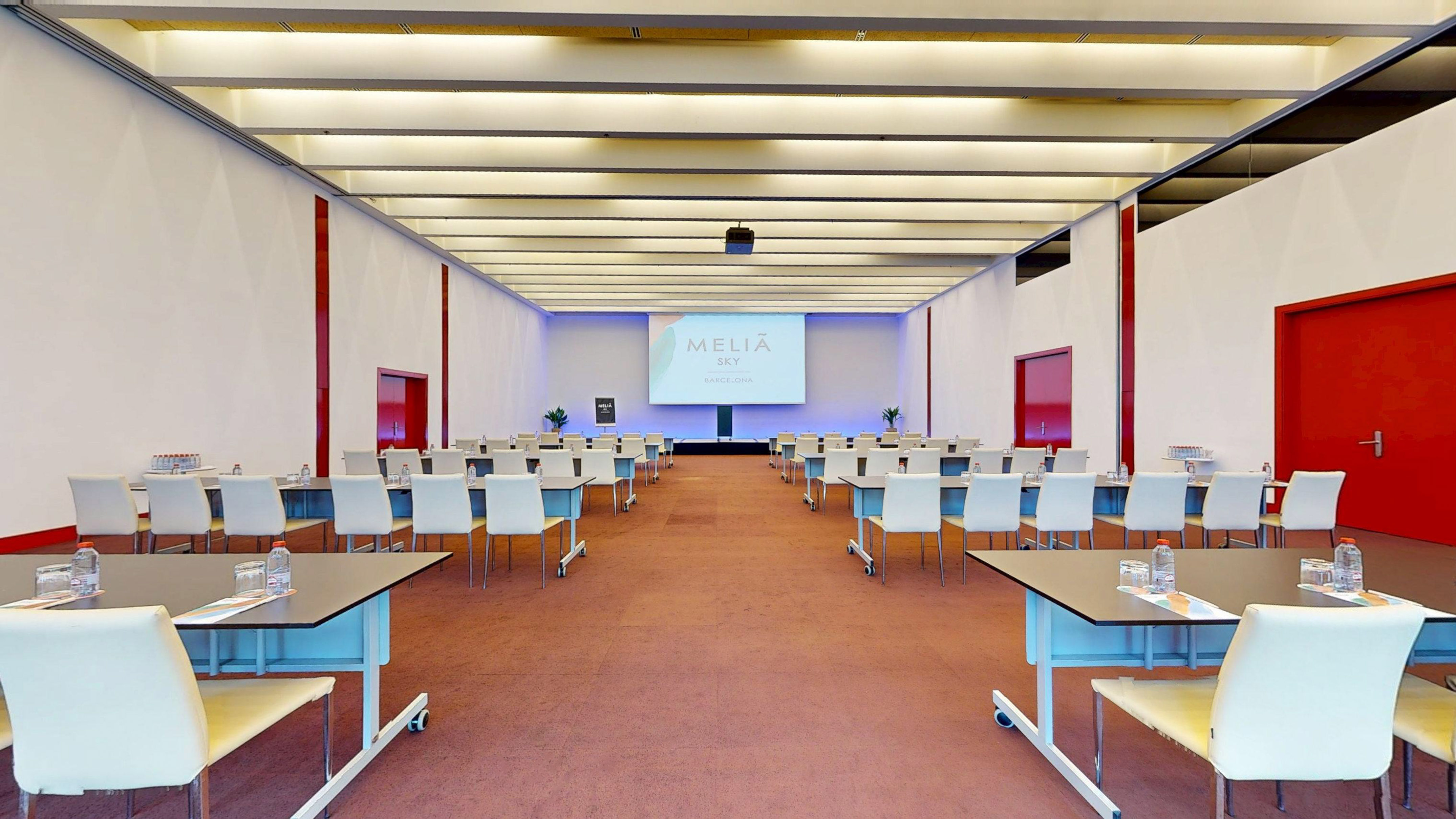 Meliá Sky Barcelona conference room with tables, chairs, and screen display.