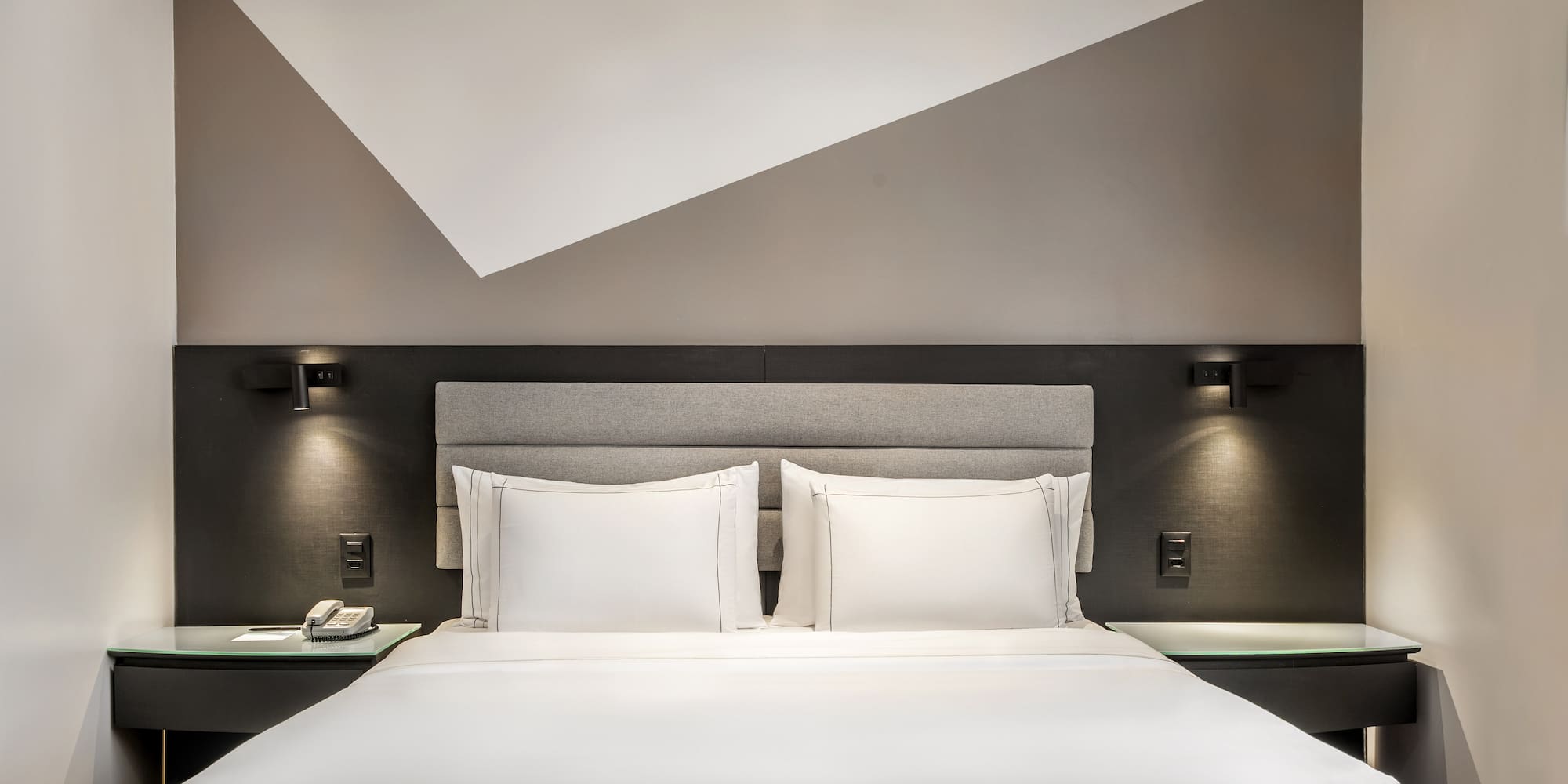 a bed with white sheets and a gray headboard