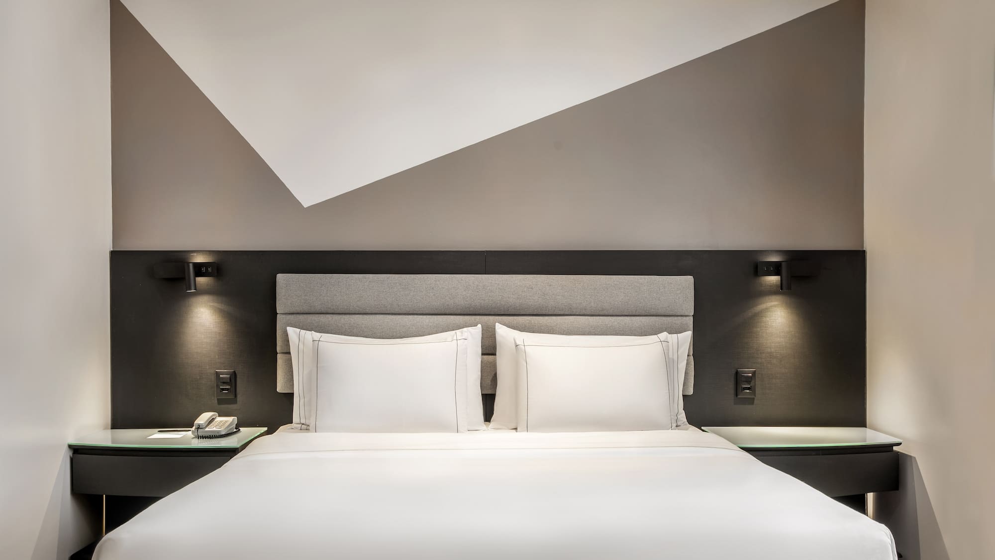 a bed with white sheets and a gray headboard