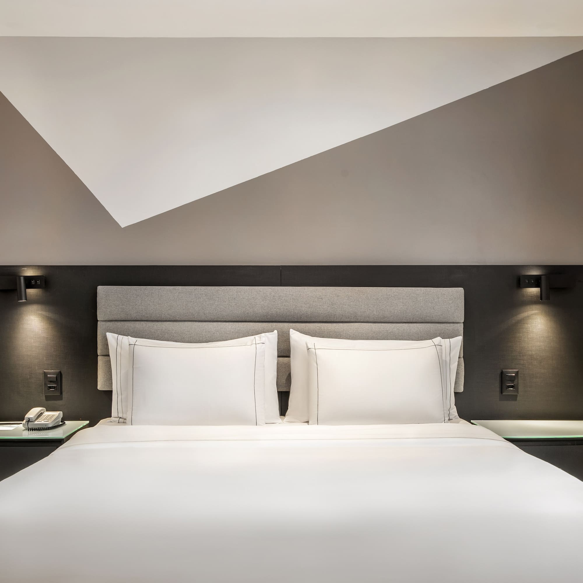 a bed with white sheets and a gray headboard