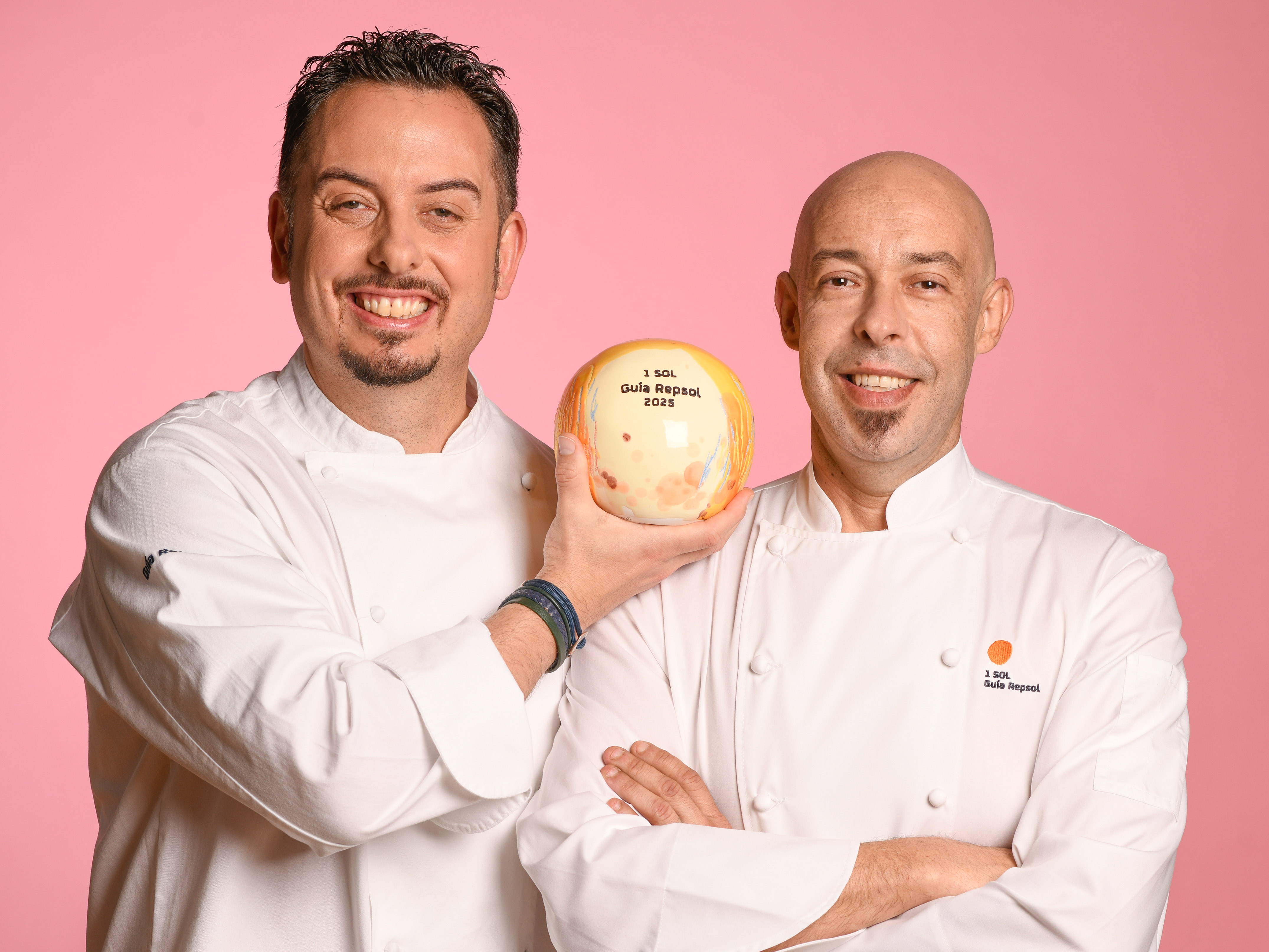 Two smiling chefs holding a 1 Sol Guía Repsol 2025 award.