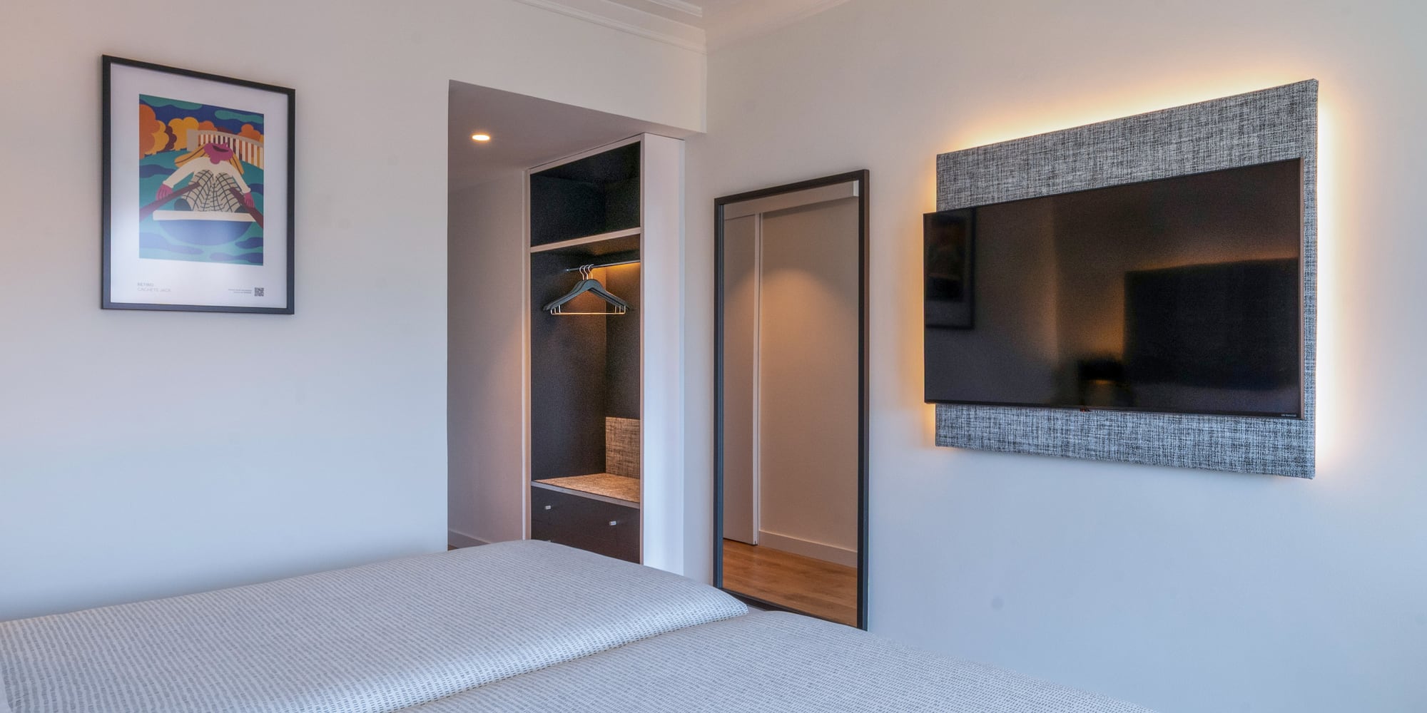 Dormitorio moderno con dos camas, TV retroiluminada, armario y espejo.