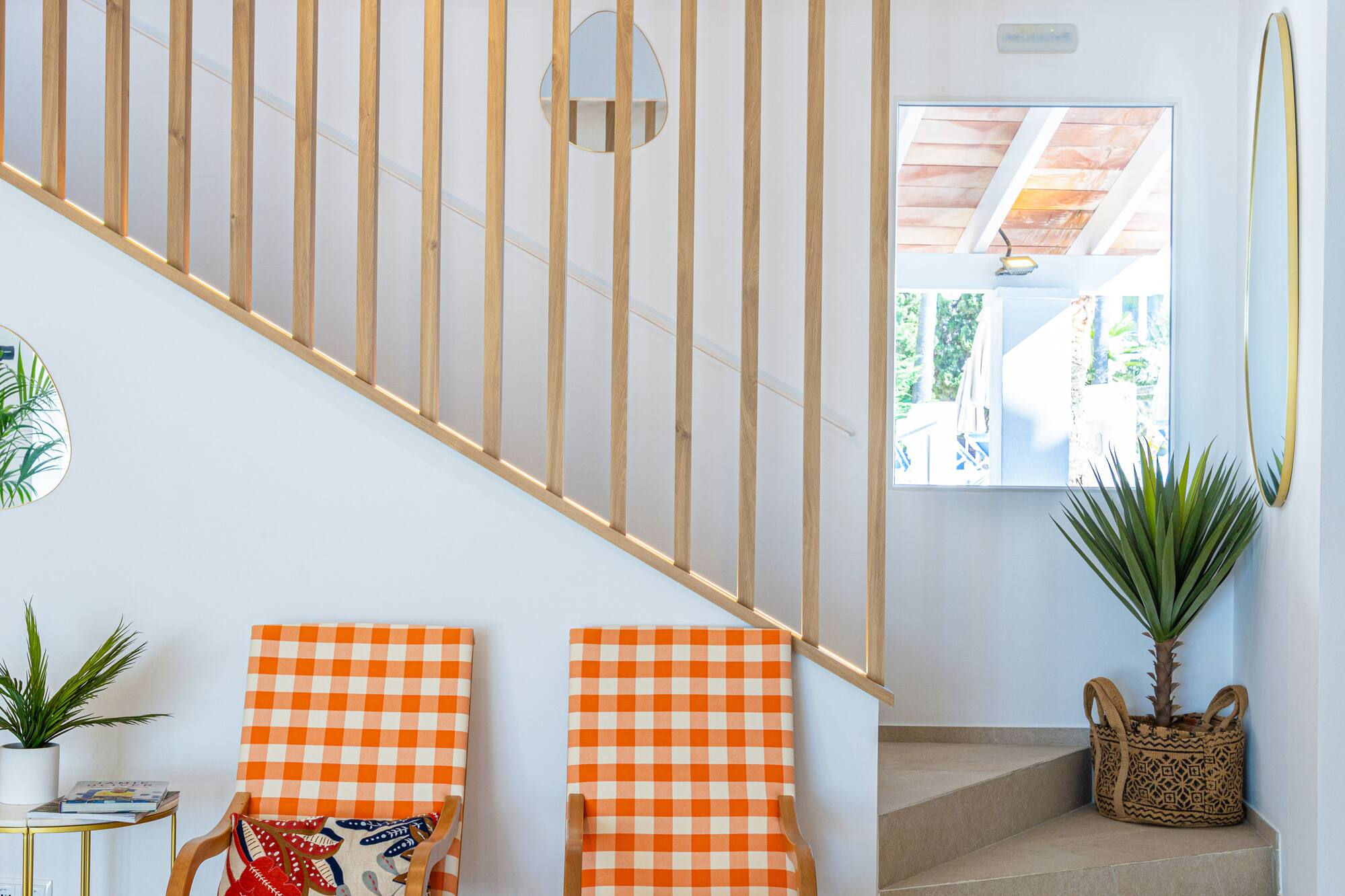 Modern interior with wooden slat staircase, orange checkered chairs, and plants.