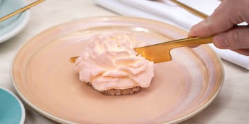 a person holding a knife over a dessert on a plate