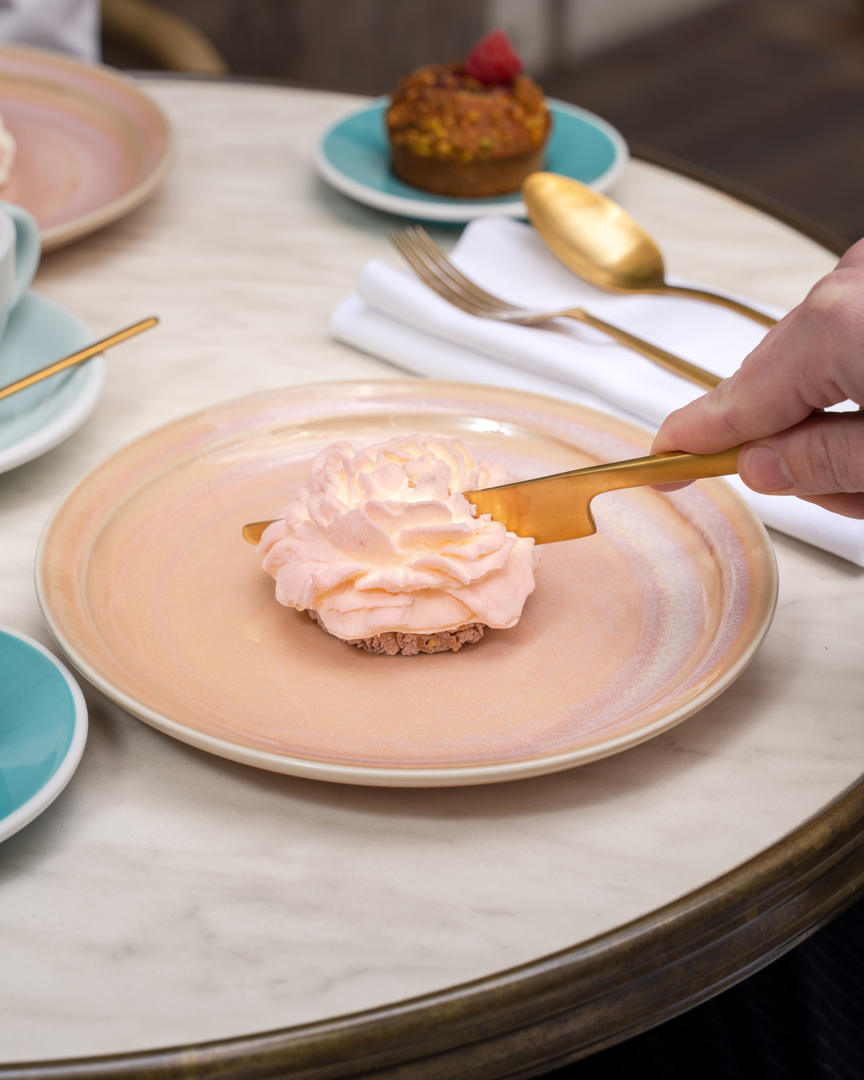 a person holding a knife over a dessert on a plate
