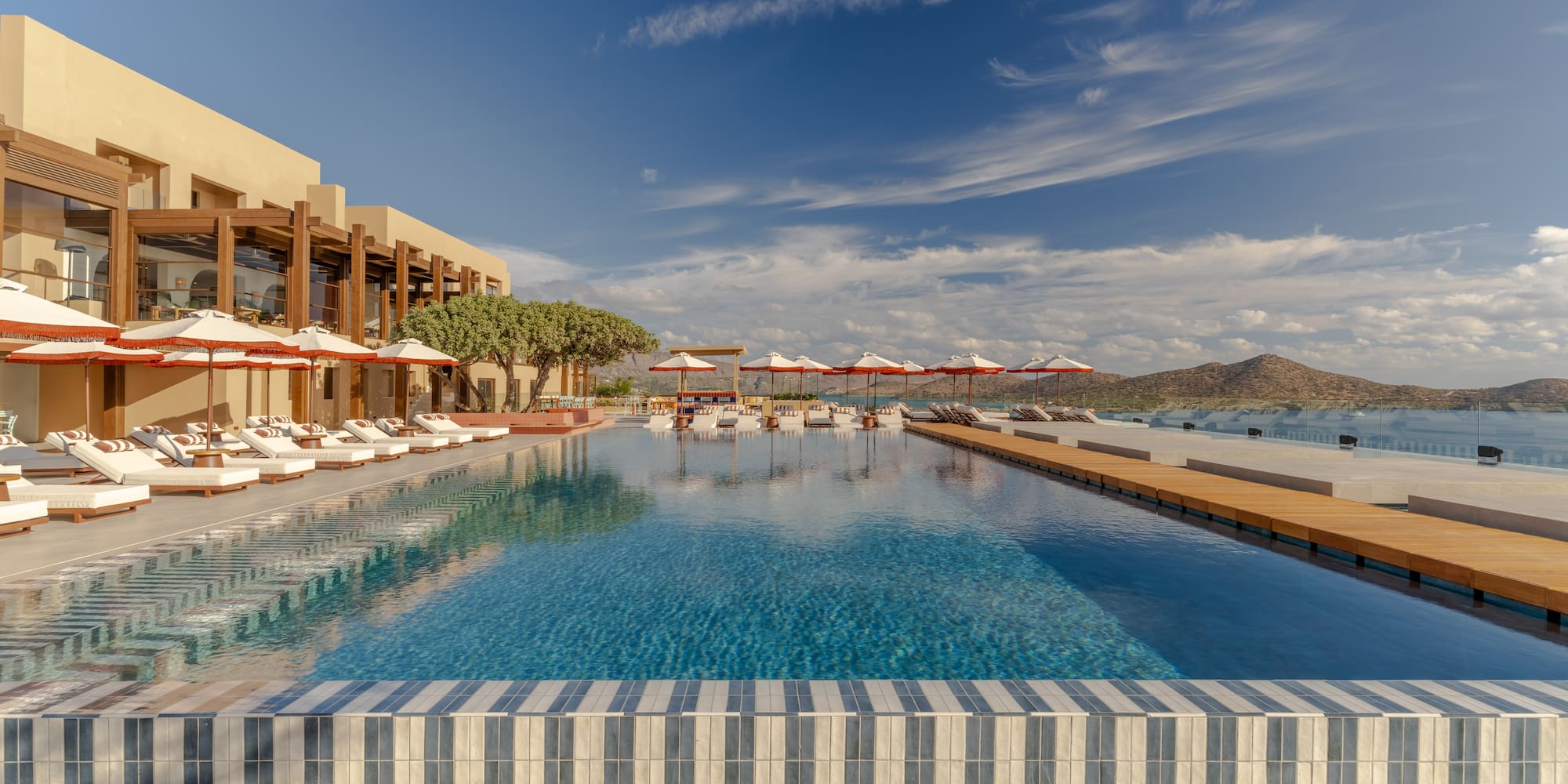 a pool with umbrellas and chairs in front of a building