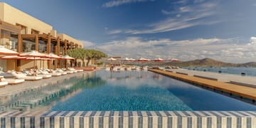 a pool with umbrellas and chairs in front of a building