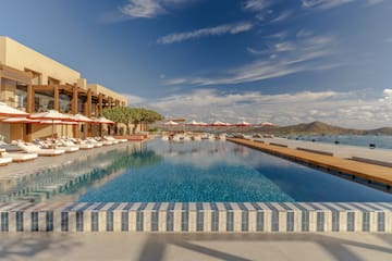 a pool with umbrellas and chairs in front of a building