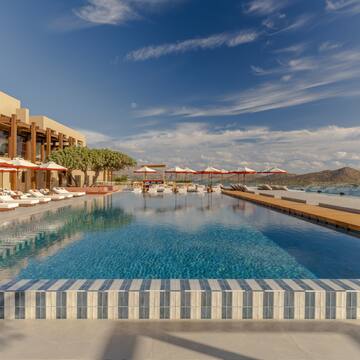 a pool with umbrellas and chairs in front of a building