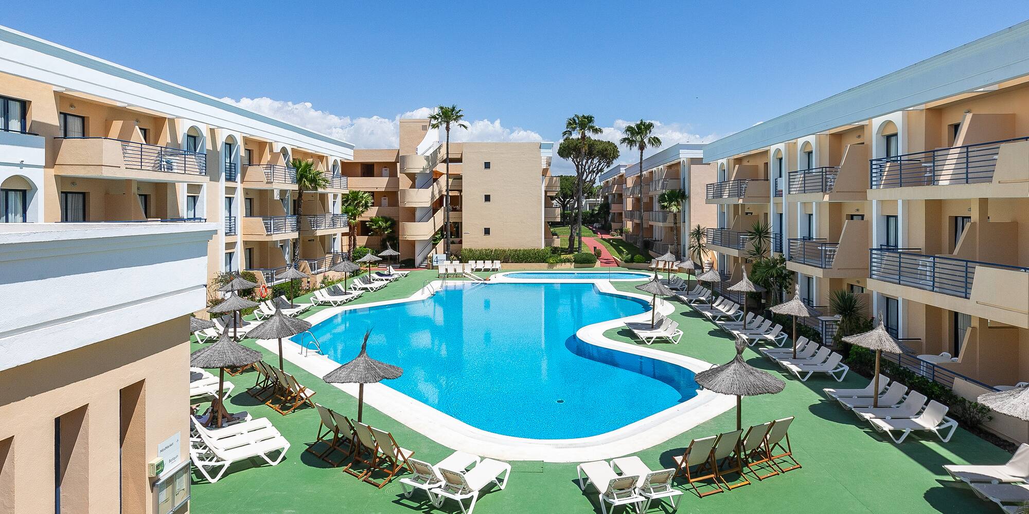 a pool with lounge chairs and umbrellas in front of buildings